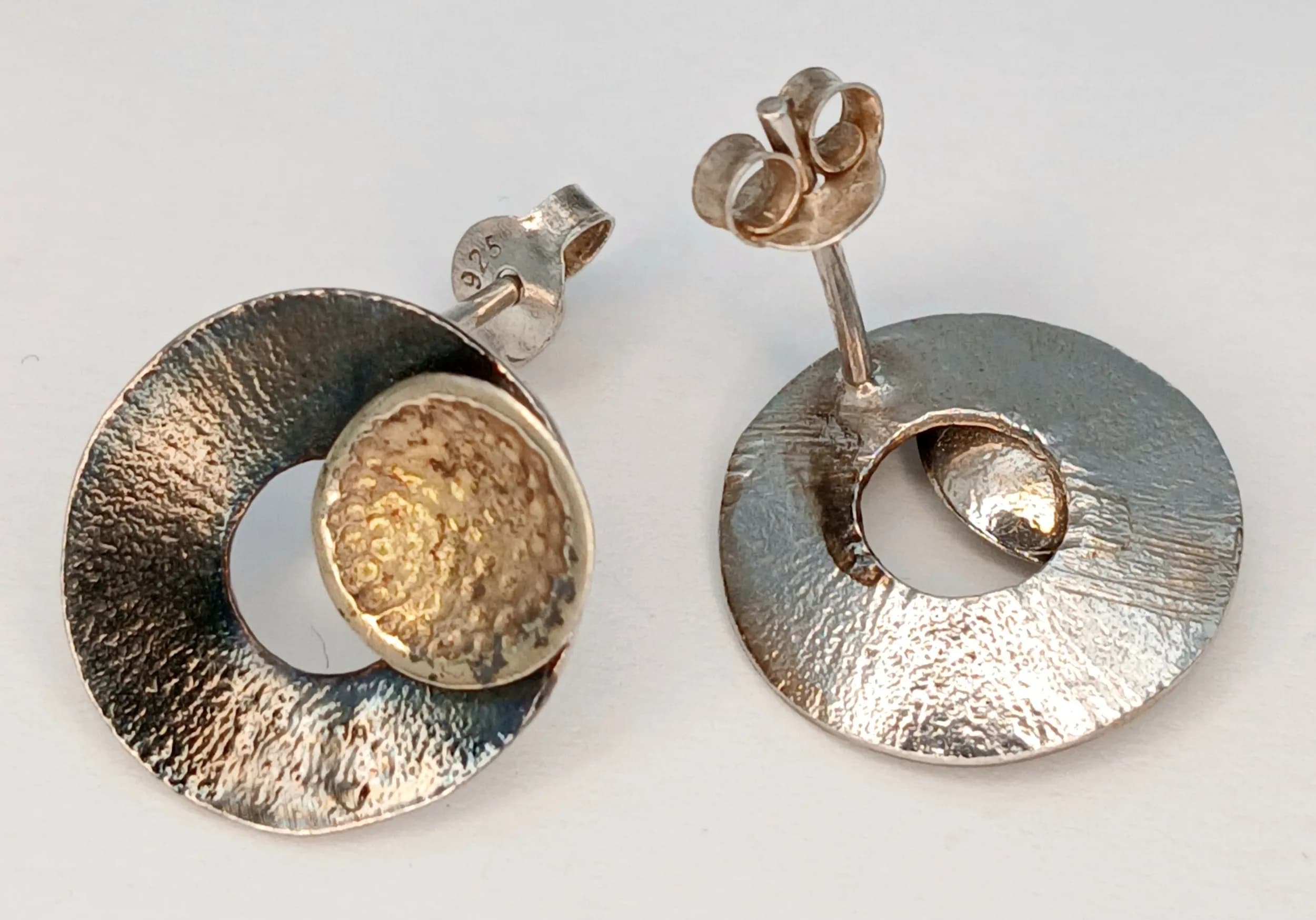 A Lovely Pair of 925 Sterling Silver Circular Stud Earrings. Features a polished circular silver design with textured centre detail and post fittings. Each earring measures 1.5cm diameter. Gross weight of earrings is 2.63 grams.