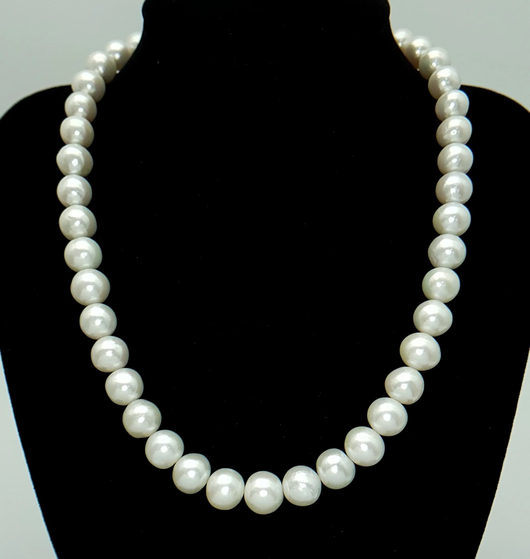A Lovely single Strand of large graduated white Freshwater Pearl Necklace, with cluster stone set infinity clasp. Approx 40cm length. Pearl 8-10 mm approx. Please see photos for details.