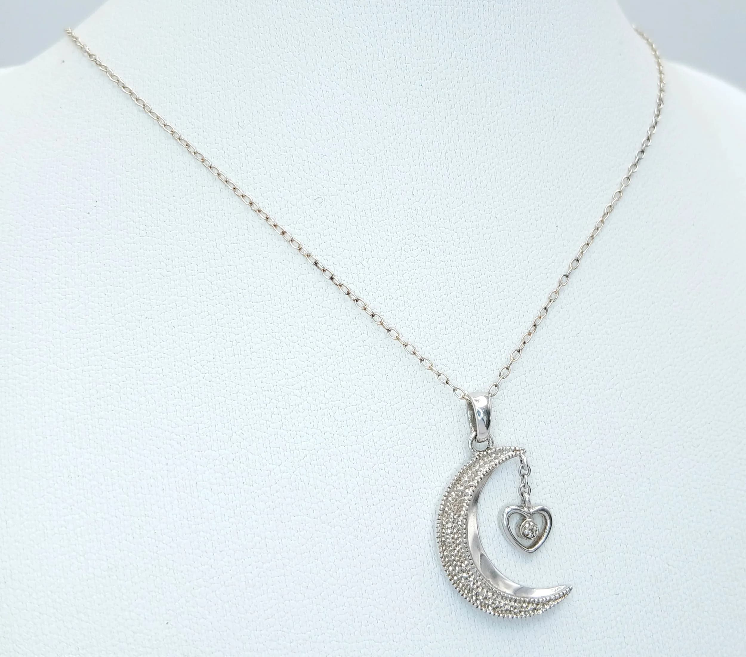 A 925 Silver Moon and Heart and Moon Pendants Necklace. Both Necklace and Pendants are Hallmarked 925. The reverse is inscribed “Granddaughter, love you to the moon and back”. Total weight 3.26g. Approx 40cm chain length with a 2.5cm pendant drop.