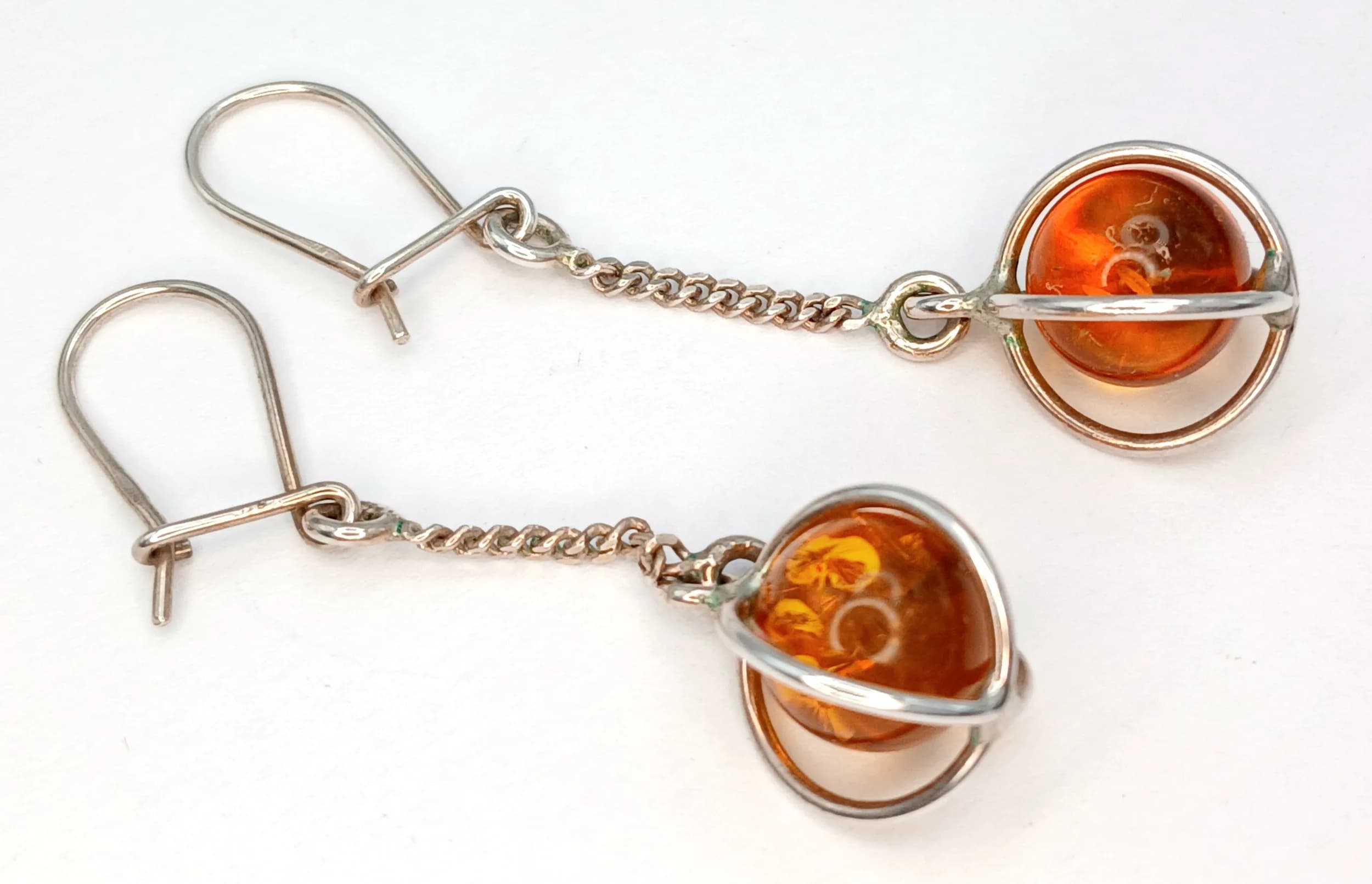 A Pretty Pair of 925 Sterling Silver Amber Drop Earrings. The Earrings each feature a Round Amber Stone in a Silver Swirl Mount with Chain Drop and Lever Back Fittings, measuring 3.5cm Drop. Gross weight 2.86 grams.