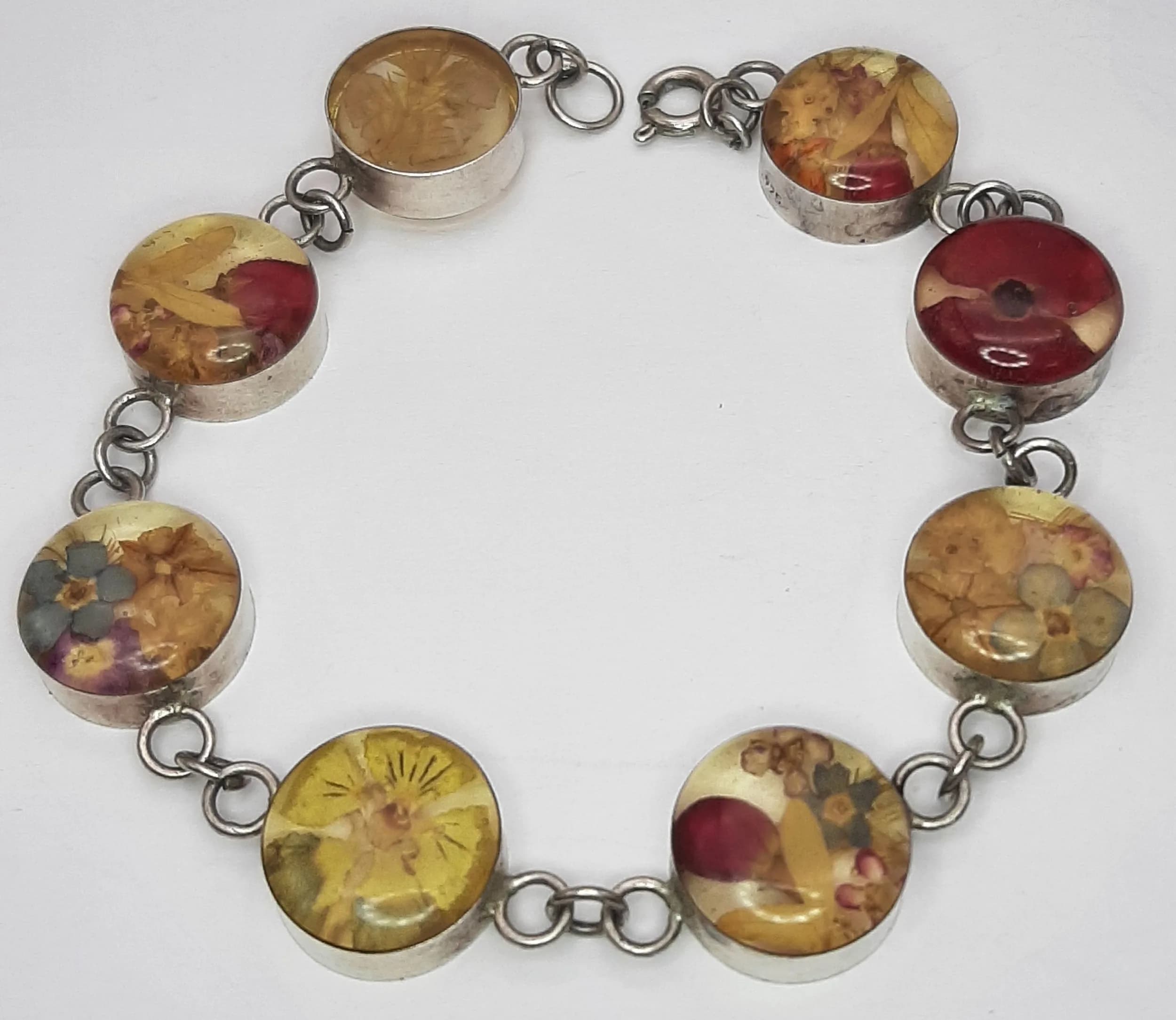 A Stunning 925 Silver Pressed Flower Resin Bracelet. Set with round clear resin panels containing pink and yellow pressed flower detail, joined by silver link sections. Approx 18cm length. Total weight 11.93 grams.