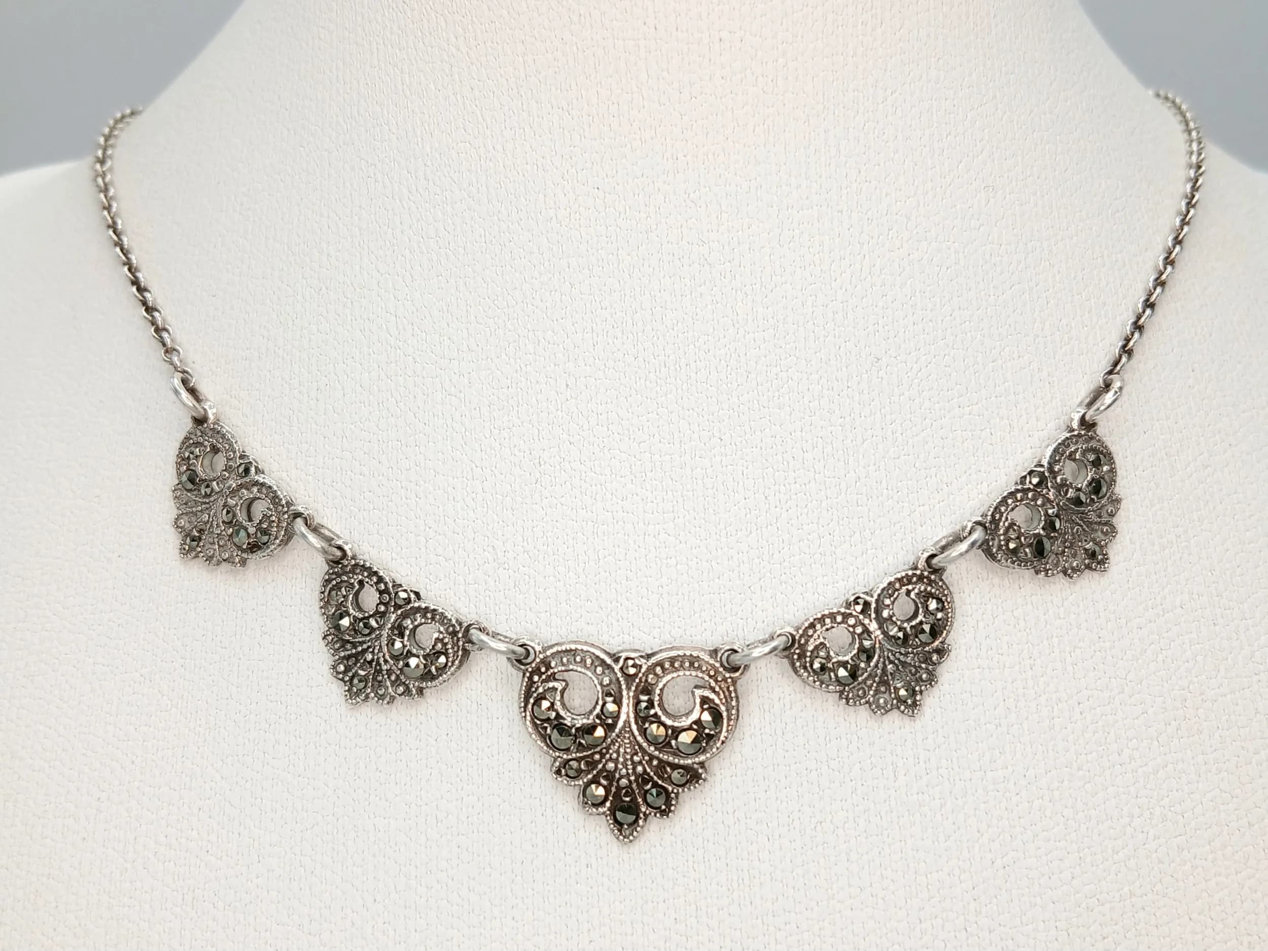 A Vintage Silver Marcasite Set Necklace - 40cm Length. Features five decorative scrollwork panels set with marcasite stones on a fine silver chain with a matching box clasp. The pendant drop measures 1cm. Gross weight 7.38 grams.