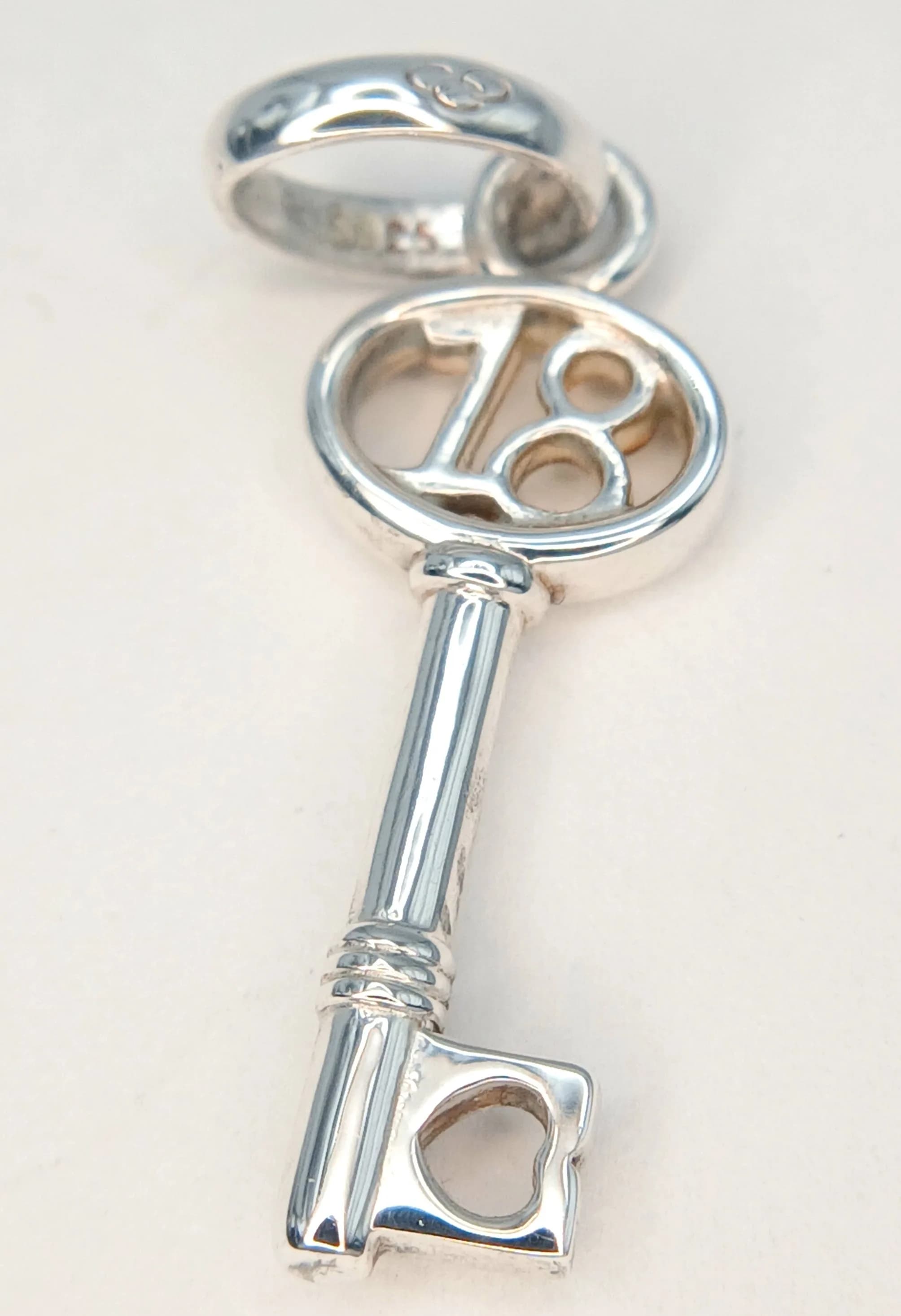 A Pretty Links of London 925 Sterling Silver "18" Key Pendant. The pendant features a key-shaped decorative silver design, with an openwork number 18 detail to the key head. The pendant measures 0.8cm x 3cm. Gross weight of pendant is 1.89 grams. Comes with the original box.
