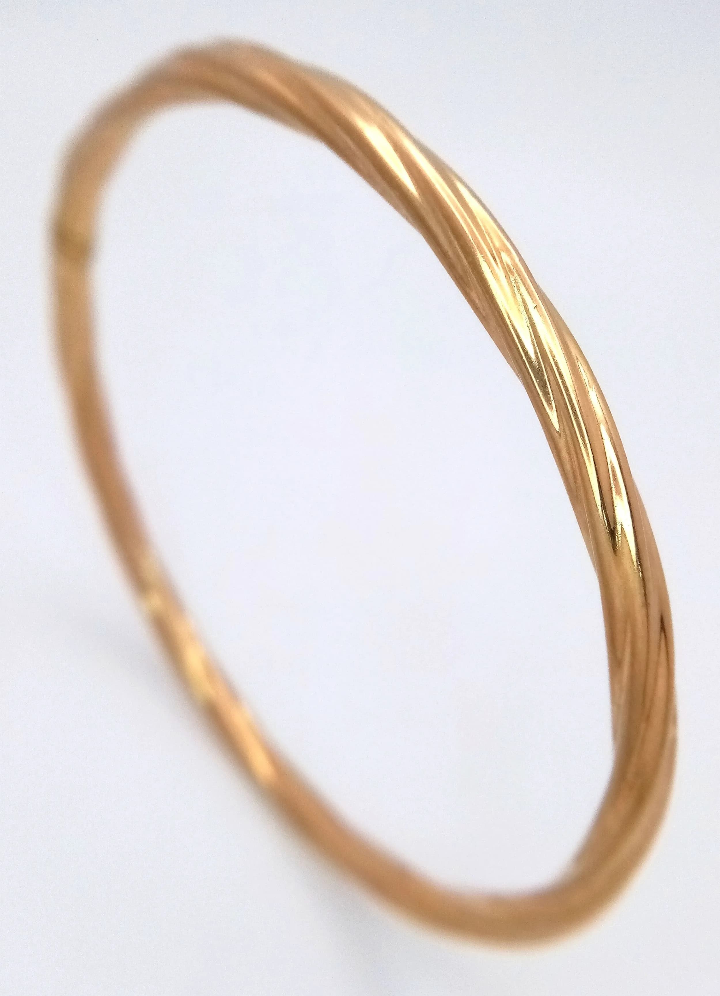 A 9K Yellow Gold Bangle with a Twist Design. 5mm width. 65mm inner diameter. 4g.