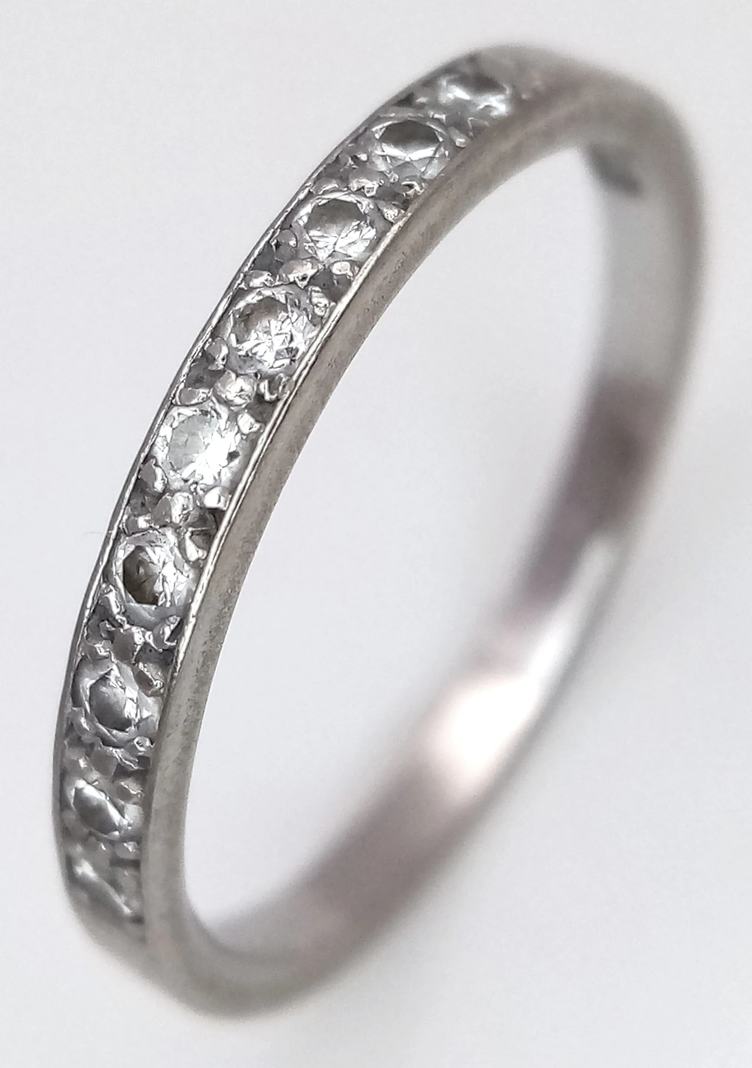 An 18K White Gold Diamond Set Band Ring. Nine diamonds. 3mm width. Size K 1/2. 2g total weight.