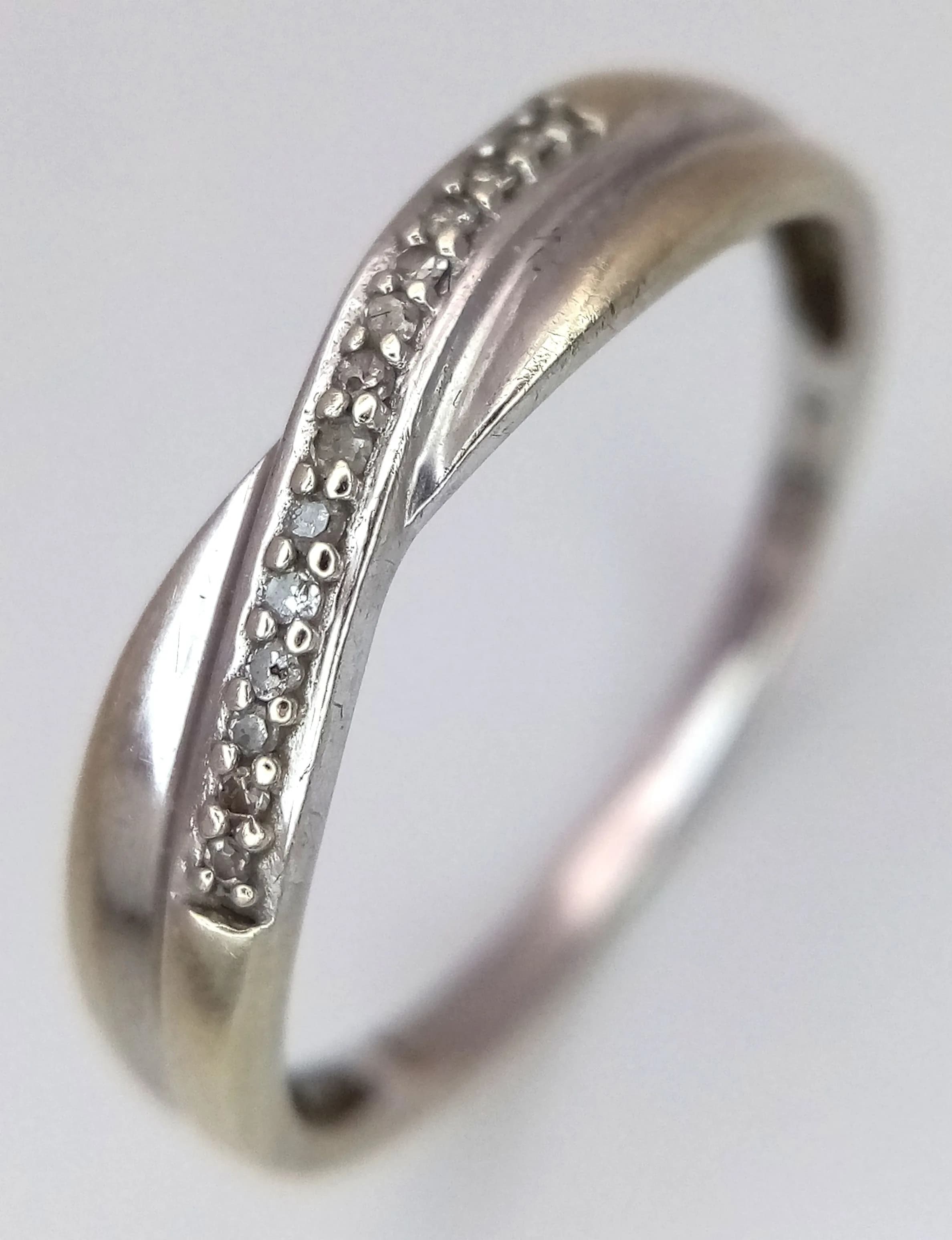 A 9K White Gold Diamond Crossover Ring. Size Q. 1.4g total weight.