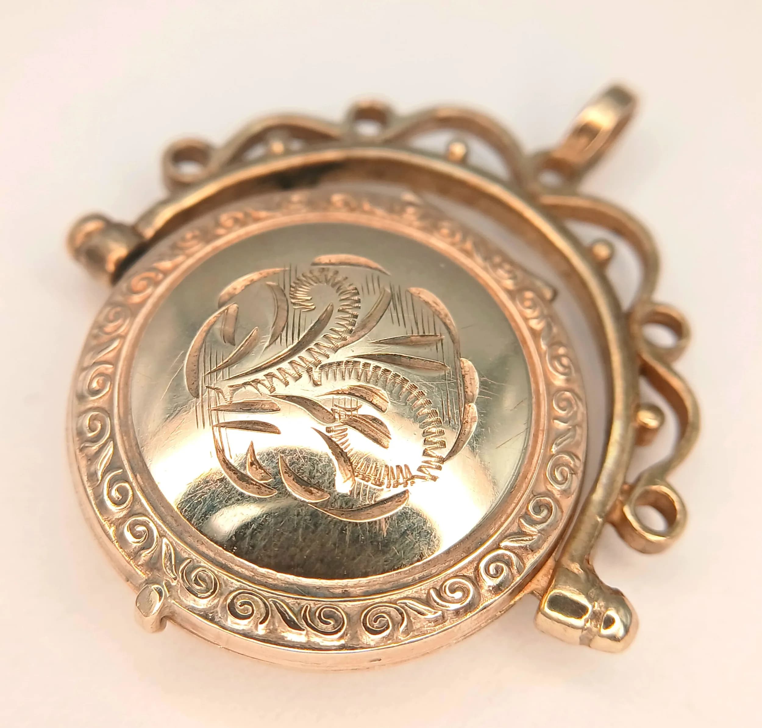 A 9K Yellow Gold Vintage Spinning Locket Pendant. Circular form with scrolled framework. 3cm. 4.1g.