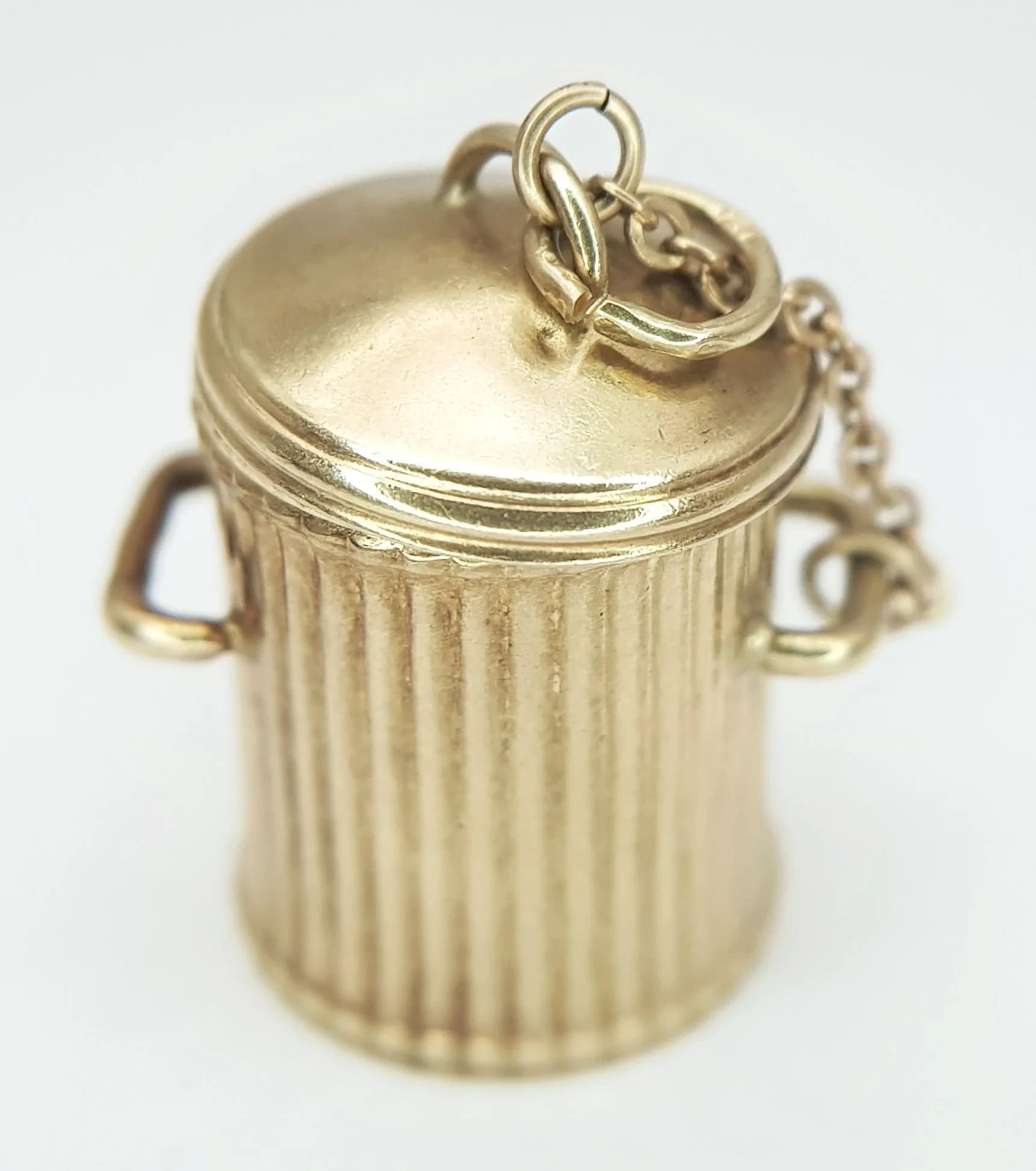 A 9K YELLOW GOLD, DUSTBIN / TRASH CAN CHARM / PENDANT. LID COMES OFF AND IS ATTACHED BY A CHAIN. 3.2G. SC 6001