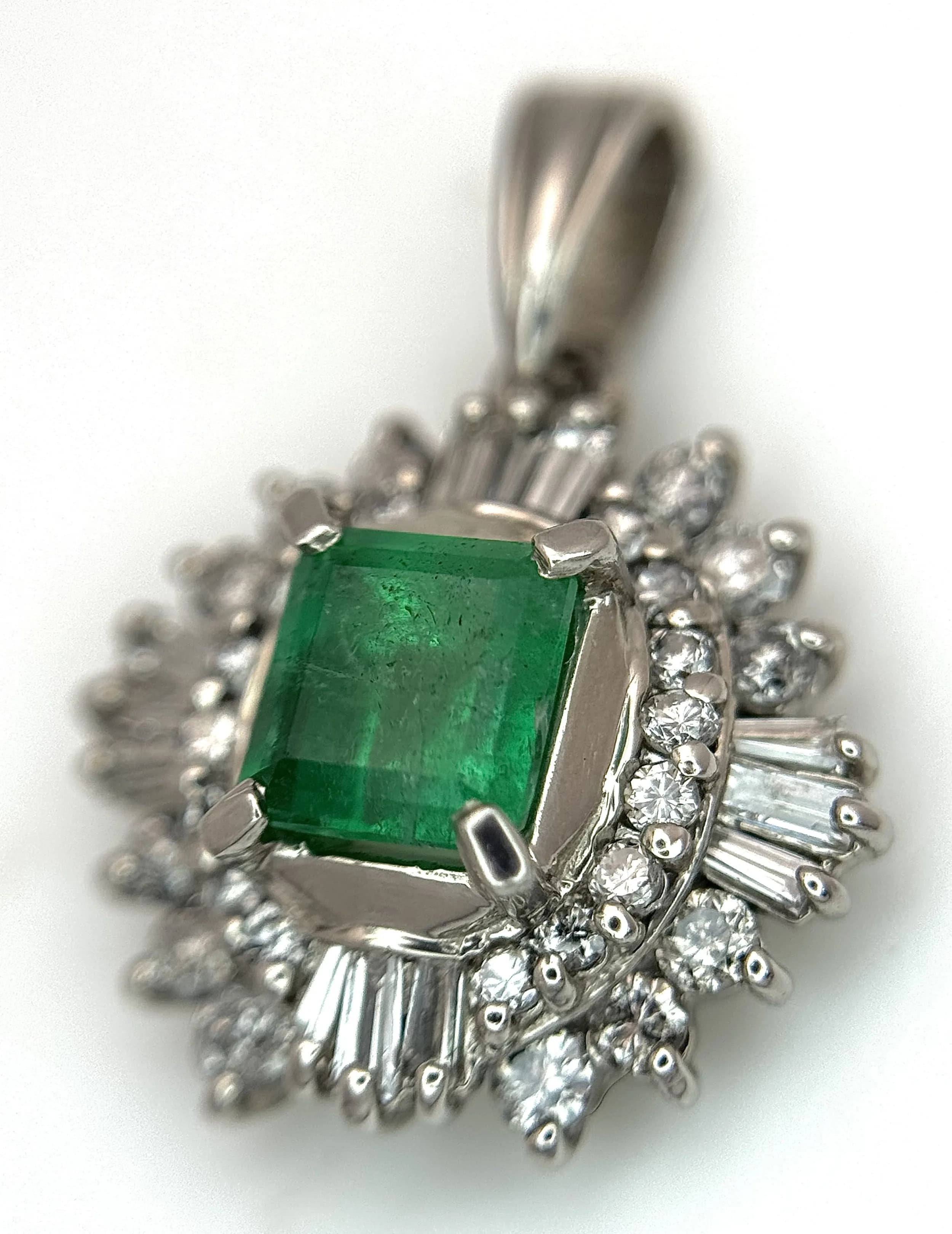 A Platinum, Emerald and Diamond Pendant. 0.61ct centre emerald with a with a c. 0.74ctw baguette and round brilliant cut diamond starburst surround. 2cm. 4g total weight. MT26.