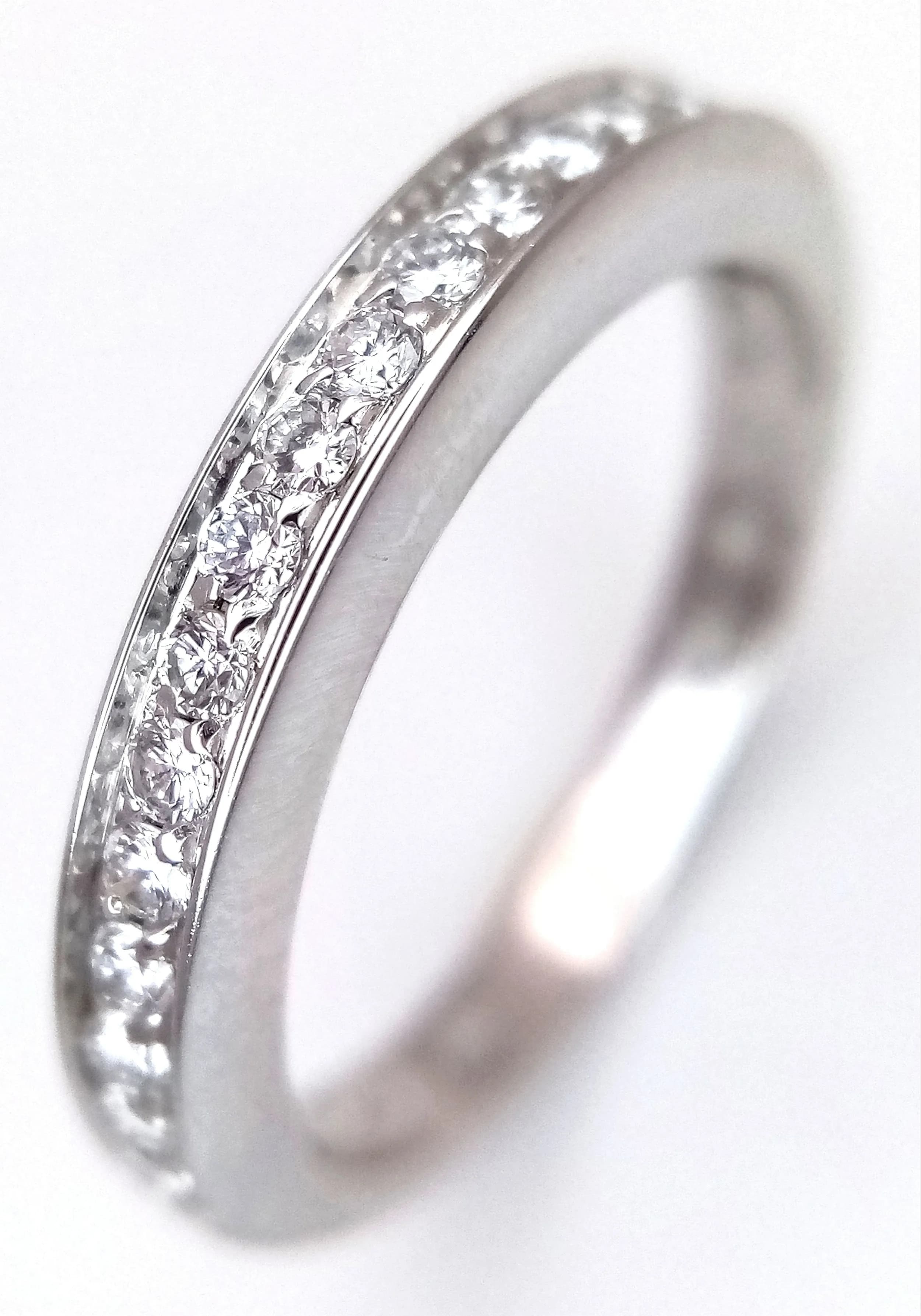 An 18K White Gold and Diamond Half-Eternity Ring. 0.30ctw of channel-pave-set round brilliant cut diamonds having F colour and VS1 clarity. Size L. 3.8g total weight. MT11.