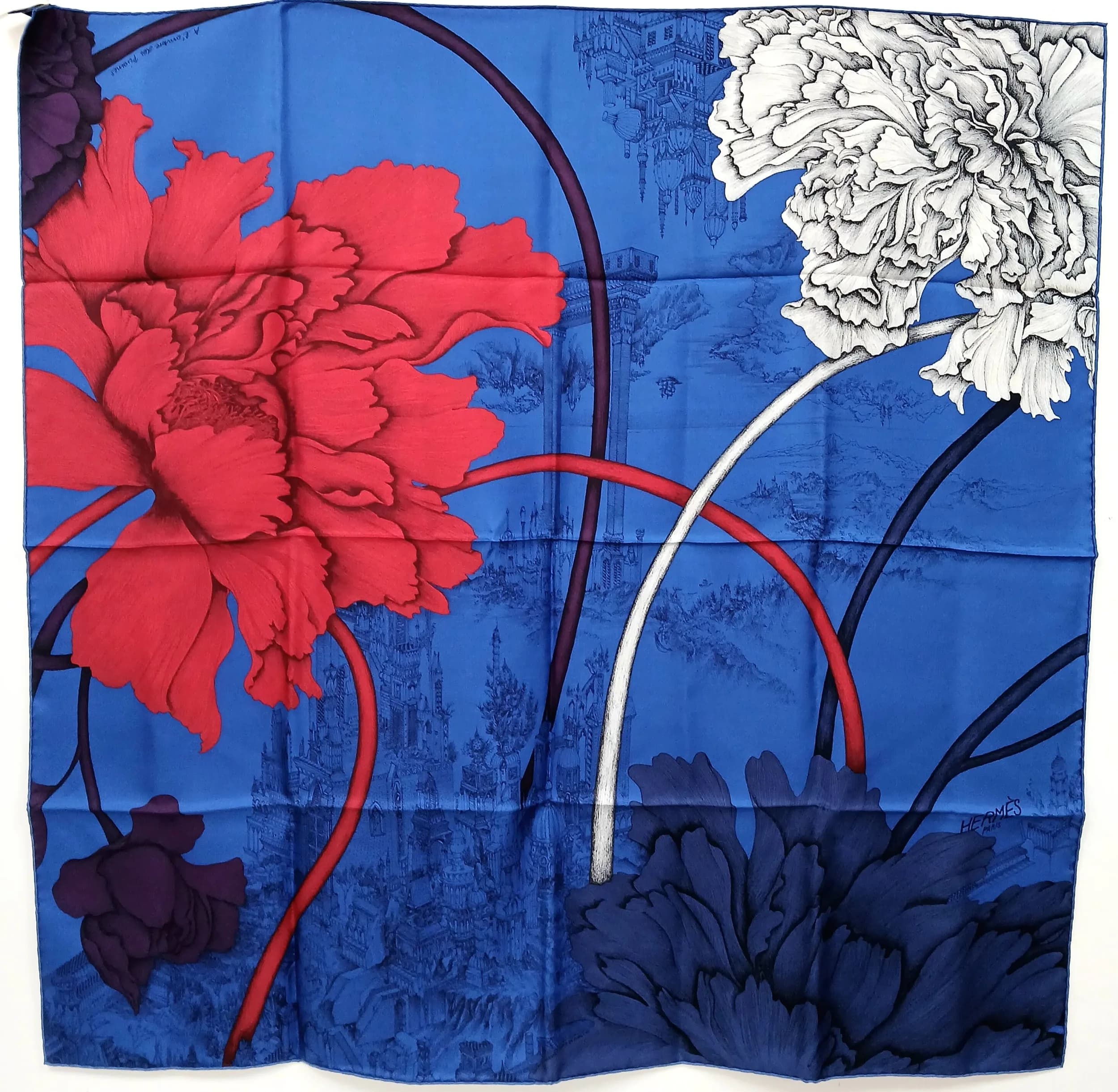 A Blue Hermès Silk Carré Scarf. Features a striking oversized red floral motif against a vibrant blue background with tonal illustrated detailing. Hand-rolled edges. Approx. 85cm x 85cm. Comes with an original tag and Hermès ribbon. Please see photos or request a condition report. Ref: 29498.