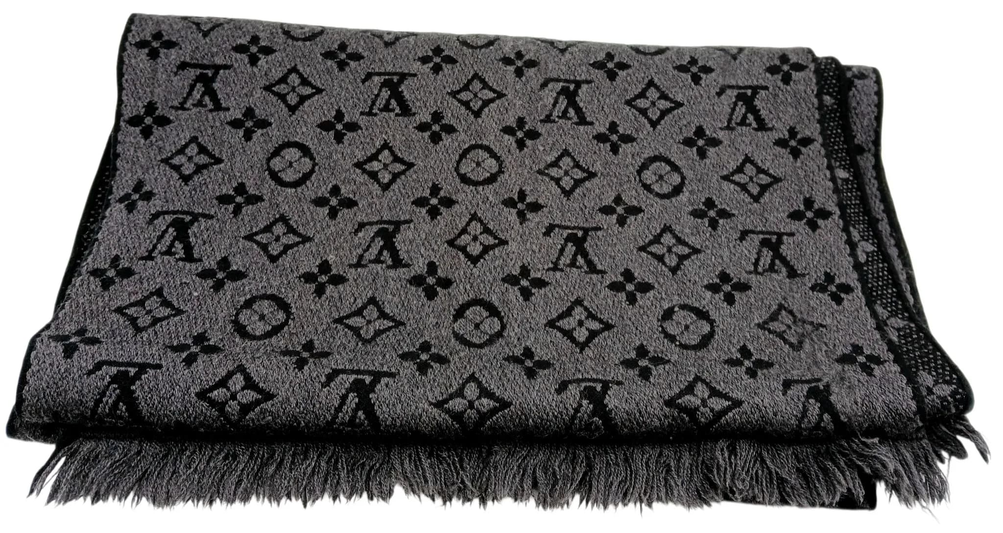 A Louis Vuitton Monogram Reversible Men's Wool Scarf. Grey wool with an all-over Monogram pattern in contrasting dark grey, finished with fringed ends. Approx. 90cm length x 36cm width. Comes with an original box. Please see photos or request a condition report. Ref: 29439.