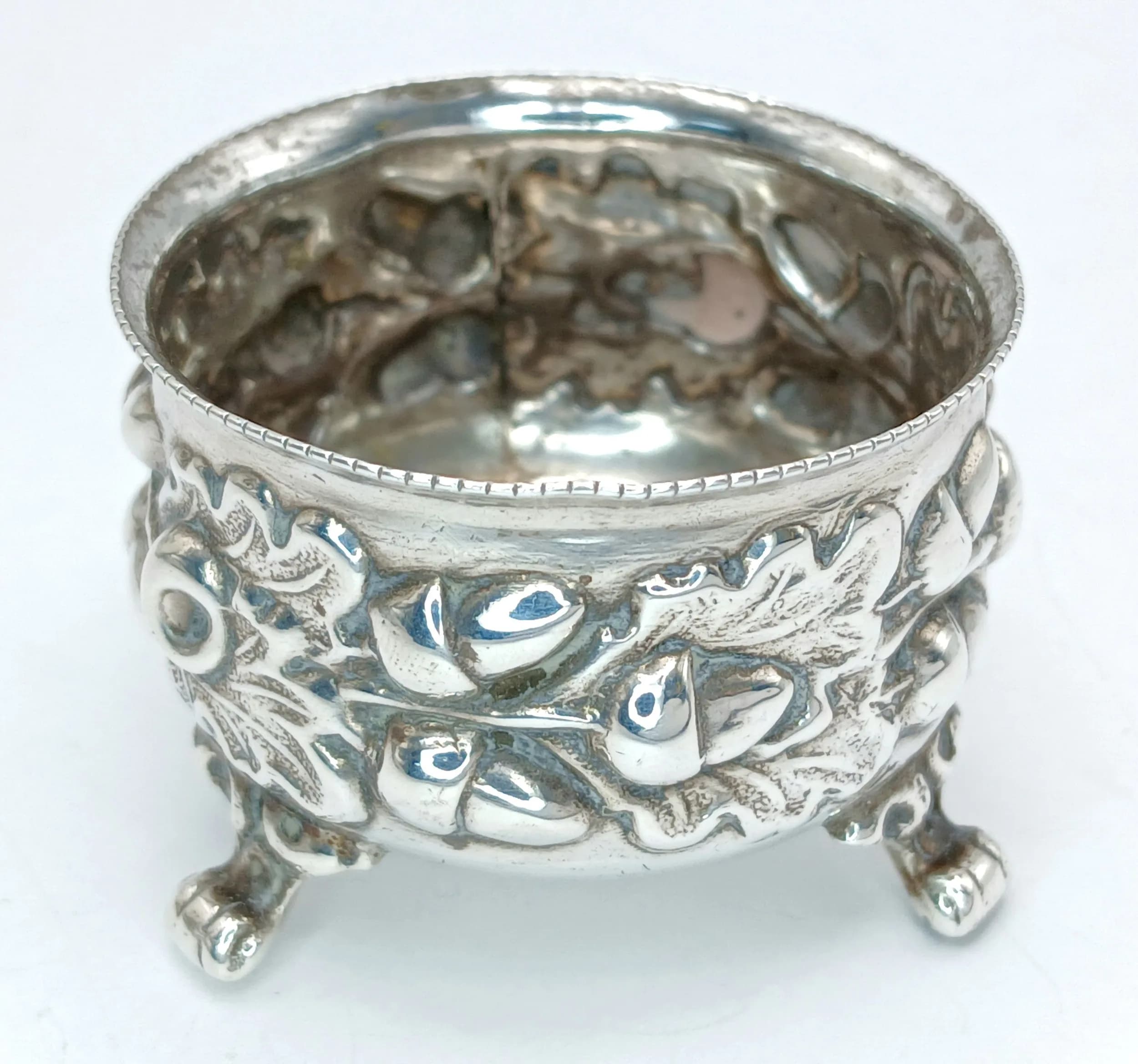 An Antique Mappin & Webb Silver Open Cellar. Raised on three pad feet with pierced floral and foliate decoration to the body and embossed floral interior. 1893 London Hallmarked . Measures approx 4cm diameter x 3cm height. Total weight 26.51 grams.