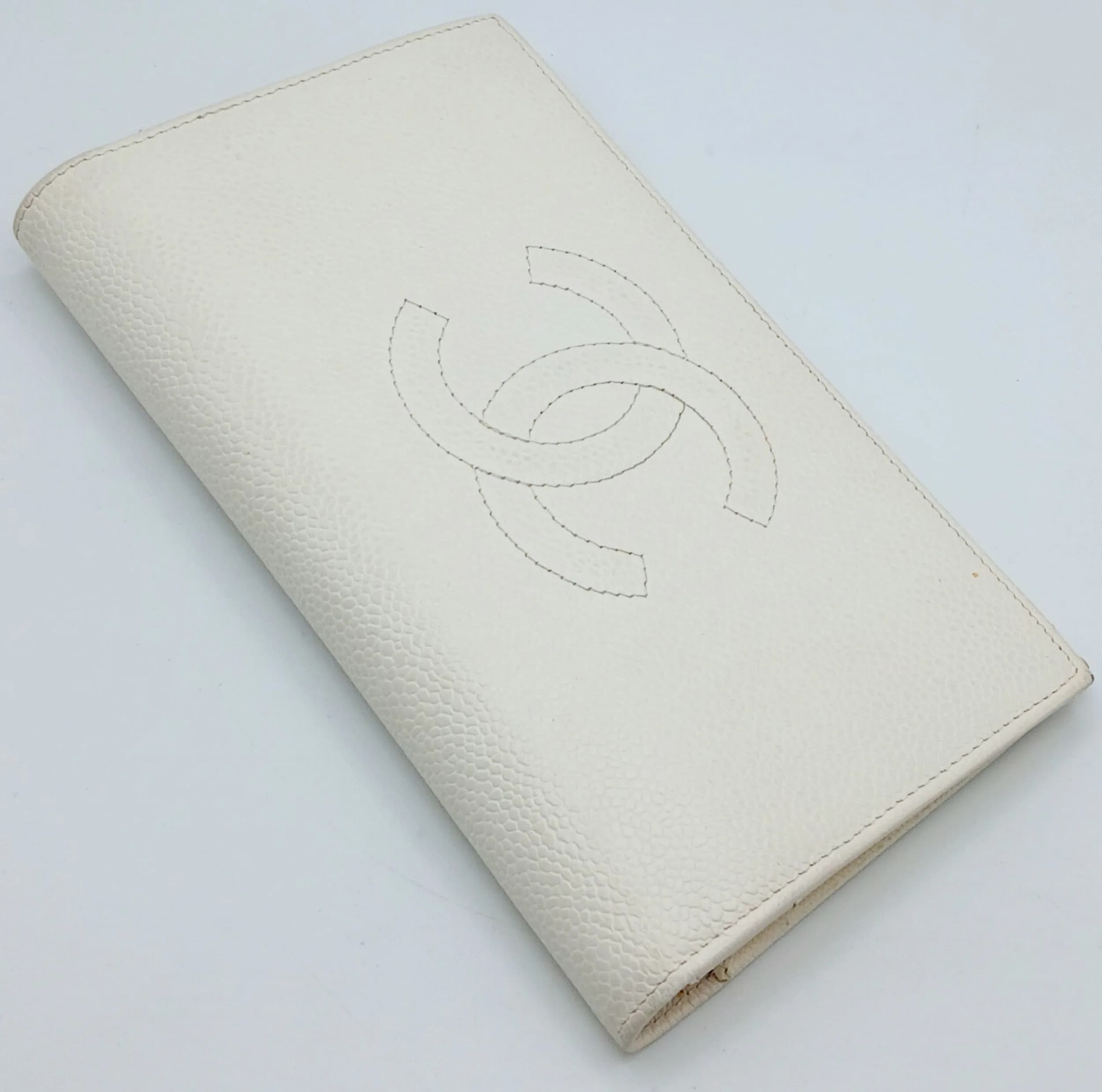 A Cream Chanel Caviar Leather Long Wallet. Cream caviar leather exterior with embossed interlocking CC logo to the front and gold-toned hardware. Cream leather interior featuring multiple card slots, note compartments and a zipped coin pocket. Approx. 18.5cm length x 10.5cm height (when closed). Some signs of wear, marks and stains to the leather. Comes with a certificate of authenticity. Please see photos or request a condition report. Ref: 29361.