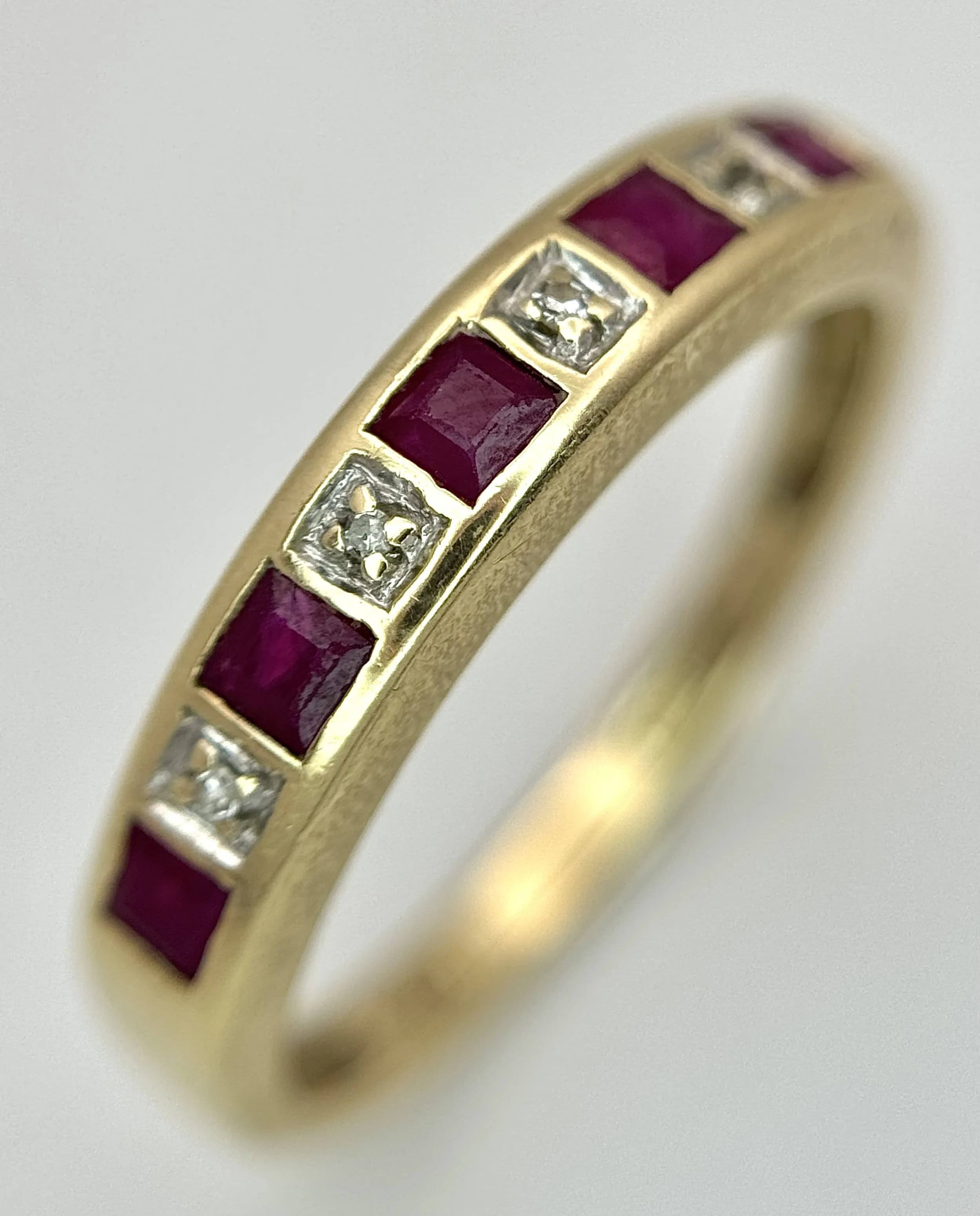 A Vintage 9K Yellow Gold, Ruby and Diamond Set Band Ring. One small diamond missing. 4mm width. Size N. 2g total weight.