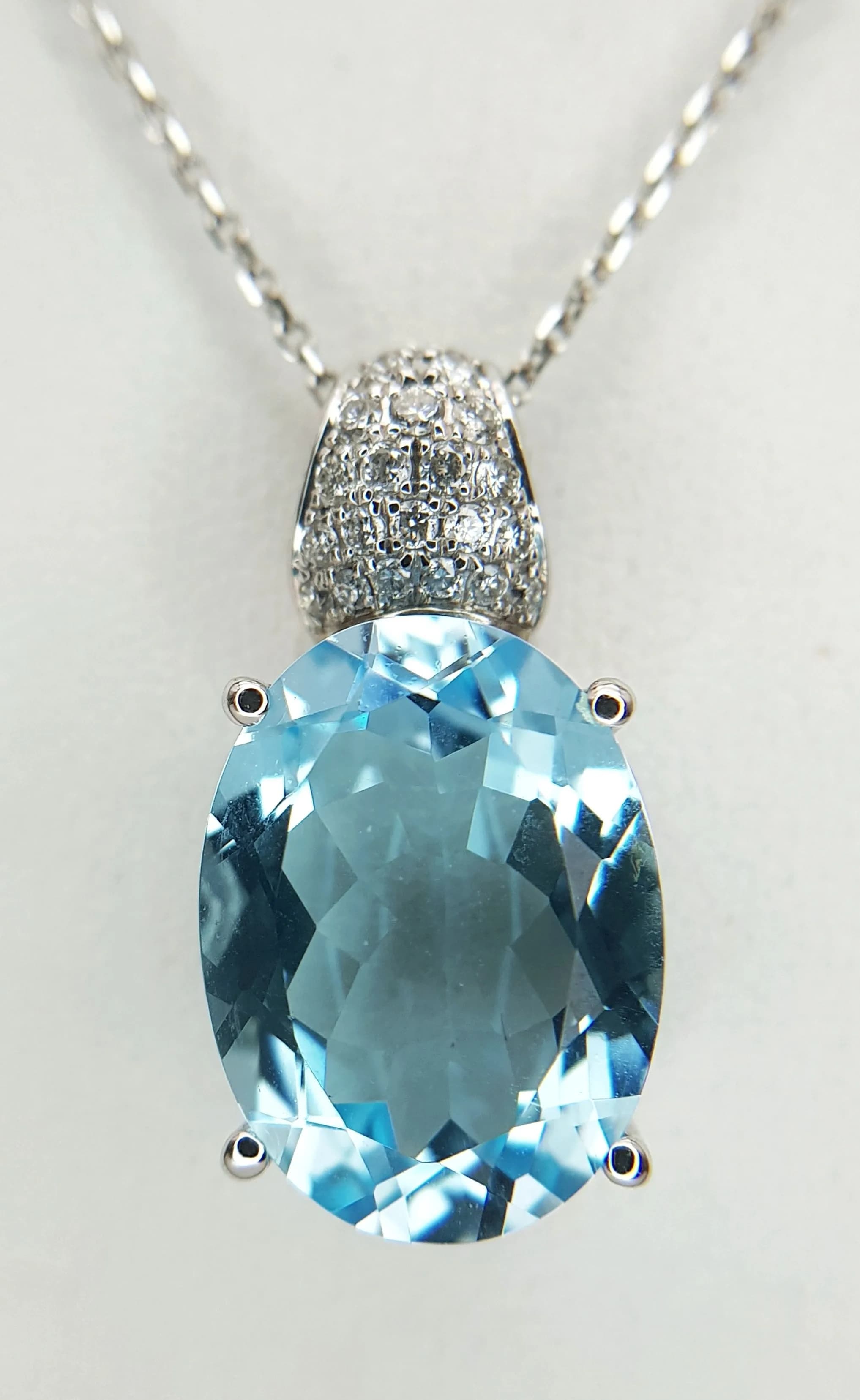A Beautiful Oval Cut Blue Topaz, Diamond and 14k White Gold Pendant on a 14K White Gold Chain. C. 12ct of ice blue faceted topaz with a diamond encrusted bail (0.44ctw). 2.5cm pendant. 44cm chain necklace. 6.1g total weight. Ref: 026549.