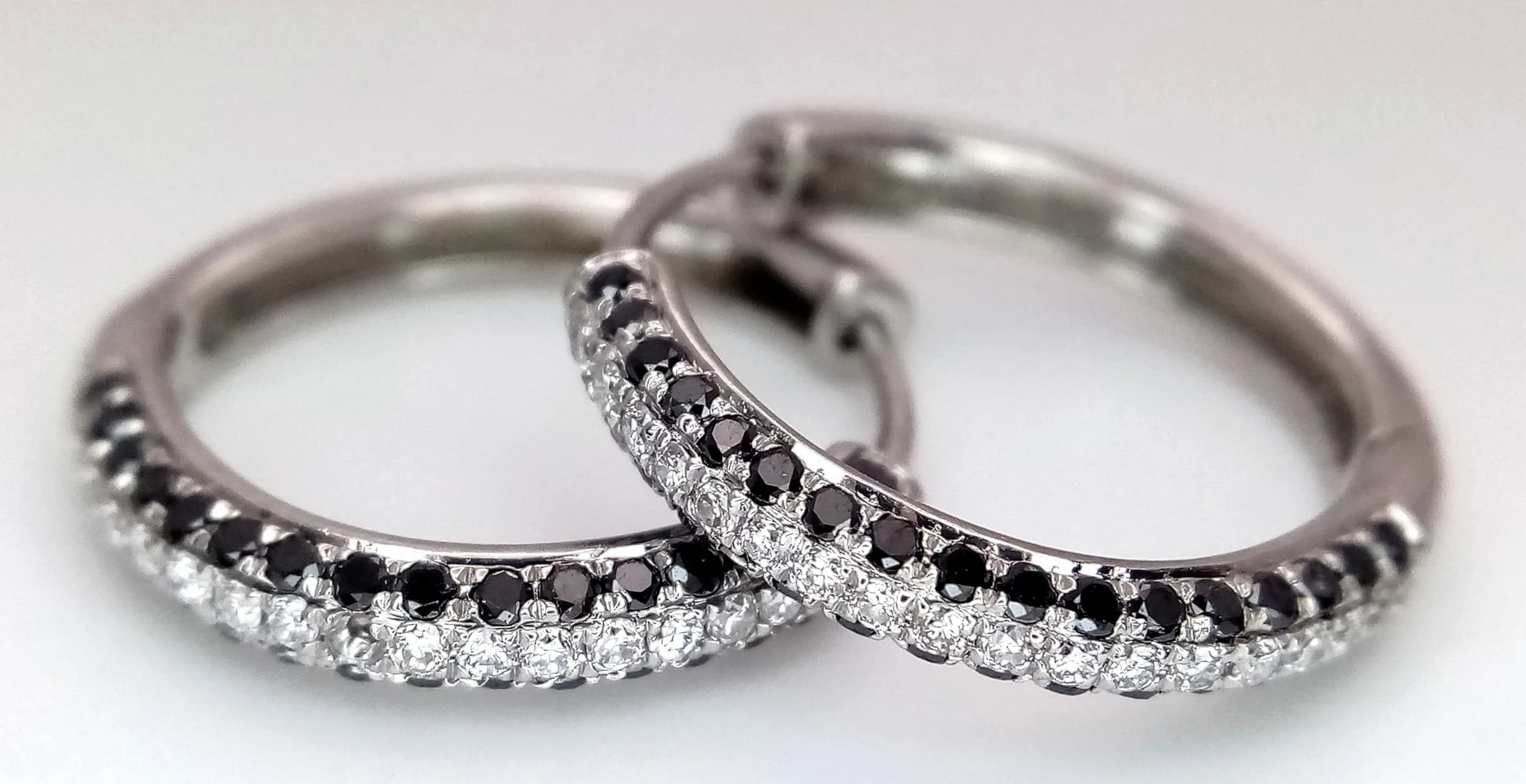 A PAIR OF 14K WHITE GOLD, WHITE AND BLACK DIAMOND SET, HOOP EARRINGS. 3.1G. J E 6002