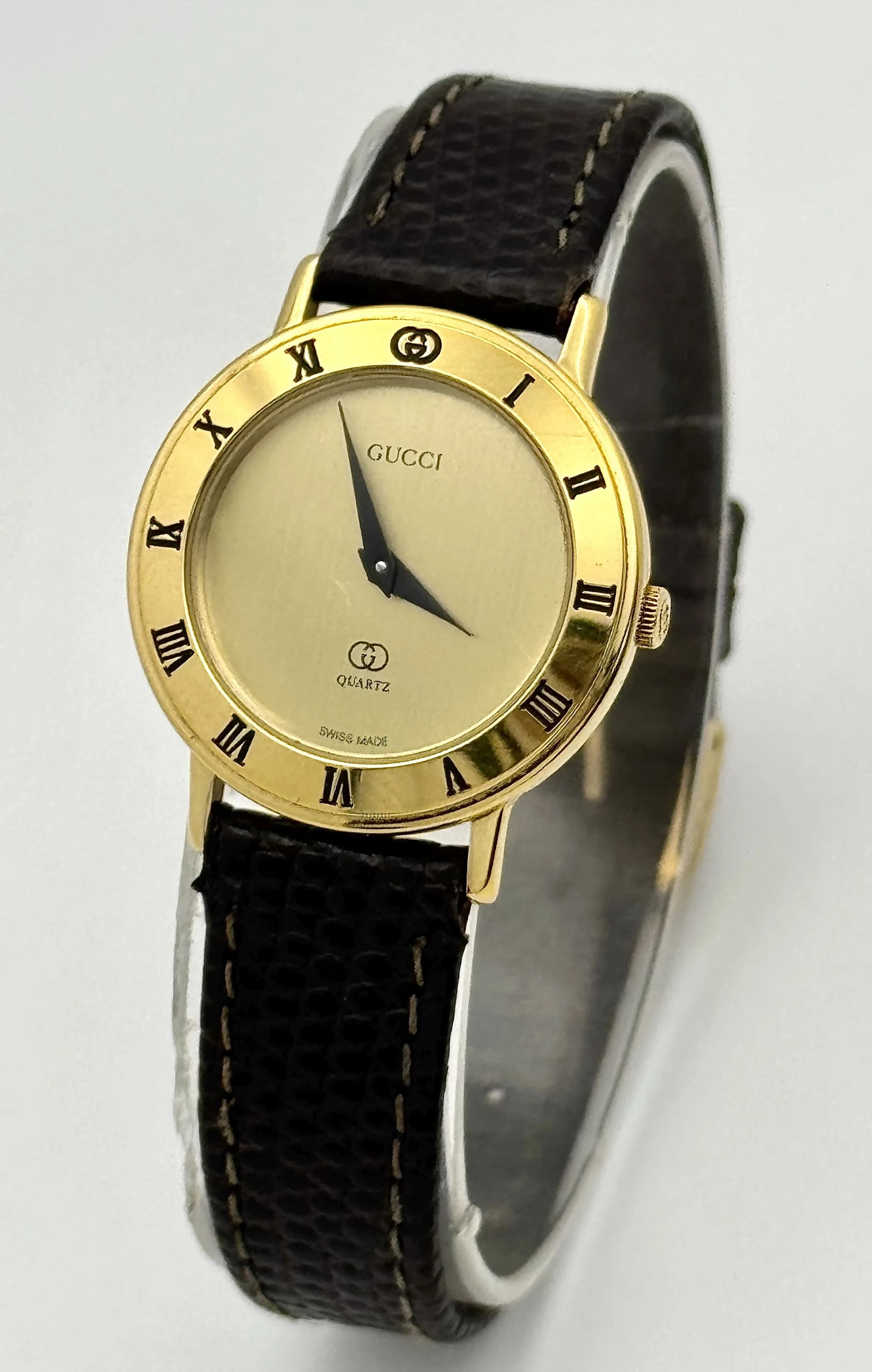 A Vintage Gucci Model 3000-L Quartz Ladies Watch. Brown leather strap. Gilded case - 26mm. Gold tone dial. Roman numeral marked bezel. New battery recently fitted. In working order. Comes with original Gucci case.