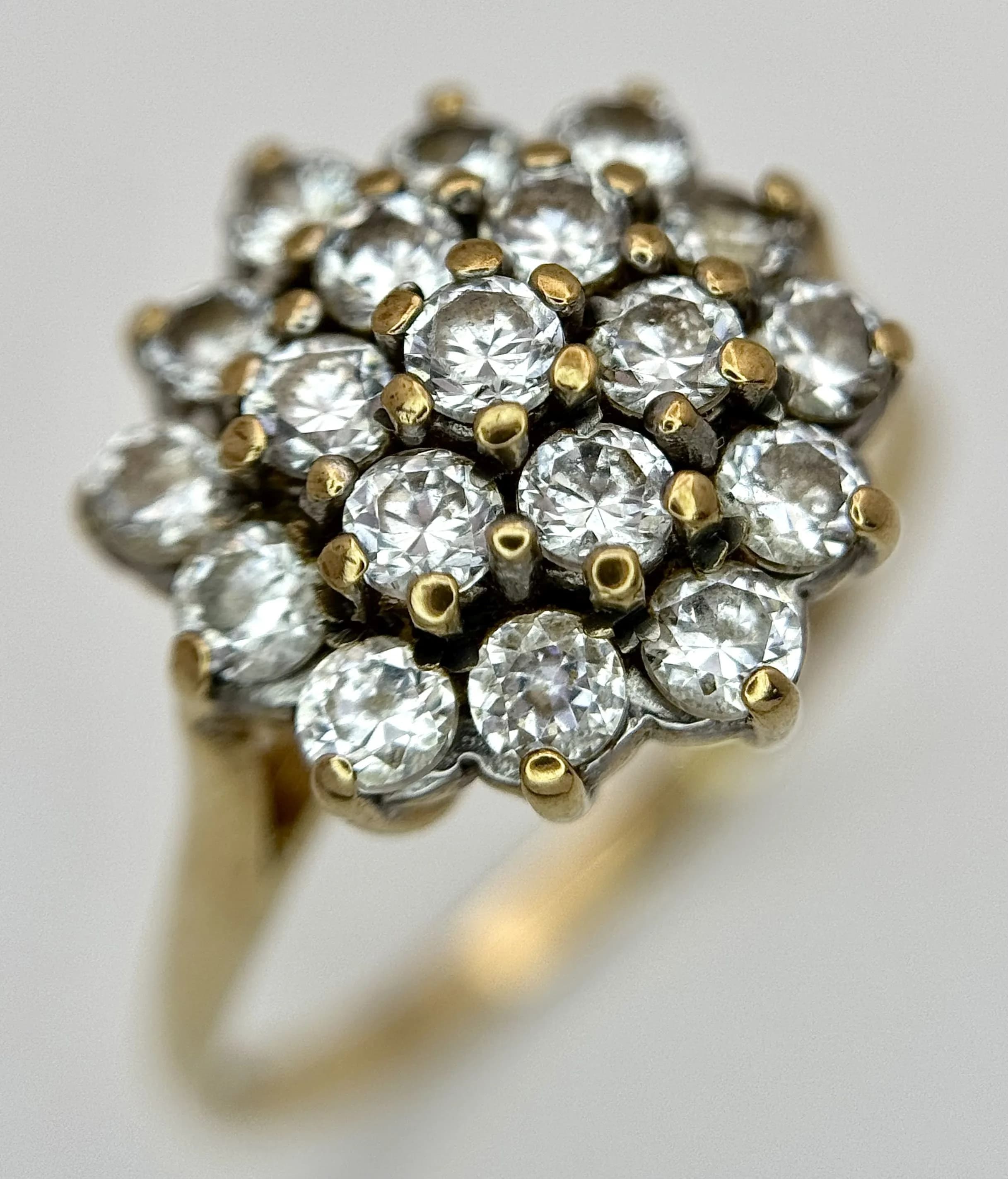 A 9k Yellow Gold Cubic Zirconia Cluster Ring. Size P. The Ring is set with tier mounted Round Cut Cubic Zirconia with the crown measuring 1.4cm Diameter. The Ring has a gross weight of 2.71 grams.