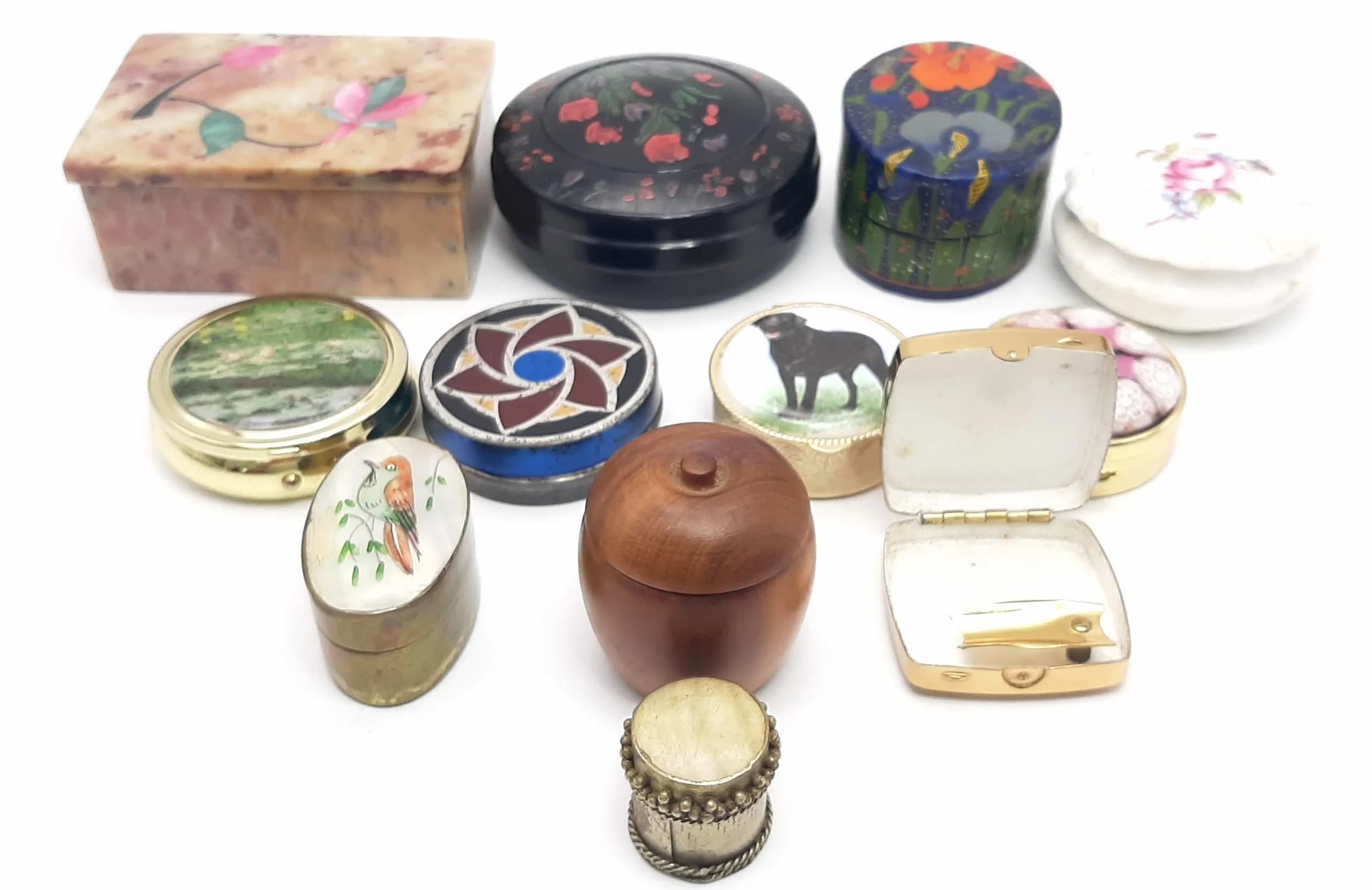 A Vintage Collection of Twelve Trinket and Pill Boxes.. Comprising 1) A Hand painted Bakelite or Similar Round Trinket Box with Crystal Decorative Insert, 2) A Coalport Porcelain Rose Detailed Trinket Box, 3) A Hardstone Enamel Inlay Floral Rectangular Trinket Box, 4) A Tin and Enamel Round Box, 5) A Gold Tone Cigarette Rest and Ash Box, 6) A Gold Tone Country Scene Three Division Round Pill Box, 7) A Gold Tone Black Labrador Three Division Pill Box, 8) A Small Gold Tone Mother of Pearl Top Box, 9) A Hand Crafted Plum Wood Box, 10) A Brass and Enamel Bird Design Box, 11) A Gold Tone Millefiori Design Box and 12) A Russian Paper Mache Hand Painted Floral Design Oval Box.