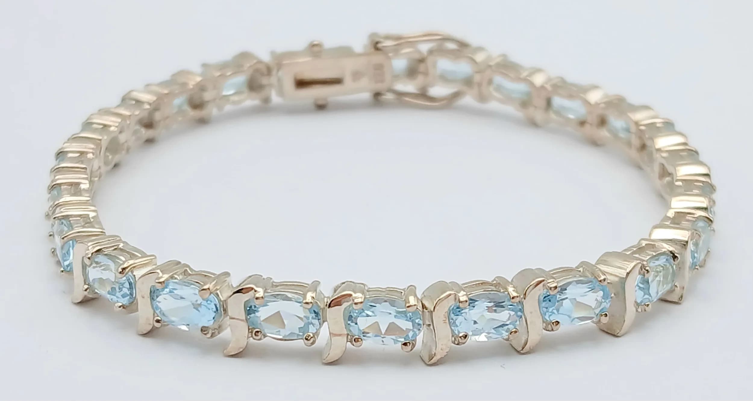 A Beautiful Sterling Silver Blue Topaz Tennis Bracelet-19cm Length. Set with Twenty-Four 6 x 4mm Oval Cut Blue Topaz, circa 9.6 carat total. The Bracelet has a gross weight of 16.42 grams