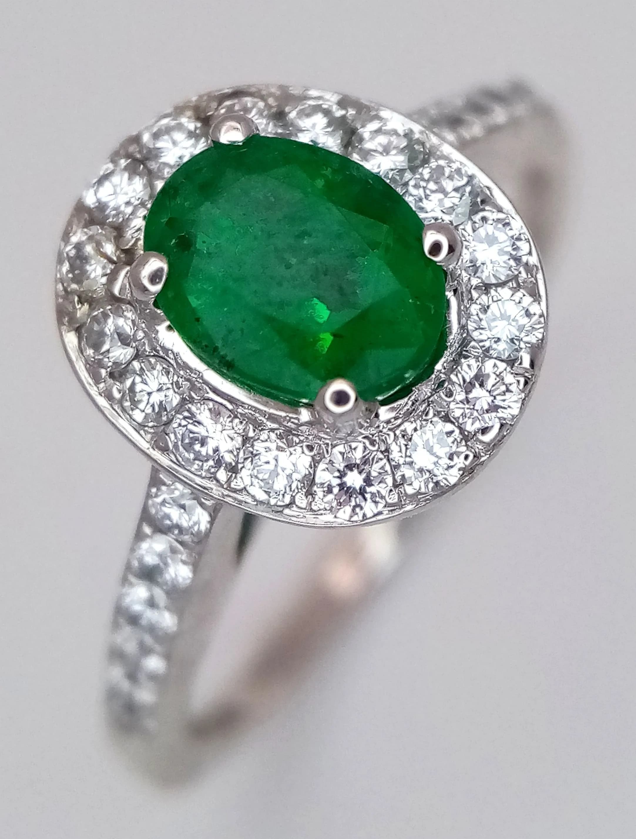 An 18K White Gold and Emerald Cocktail Ring. A 0.80ct oval cut Zambian Emerald with a 0.35ctw diamond surround having F colour and VS2 clarity. Size O. Size P. 3.7g total weight. MT24.