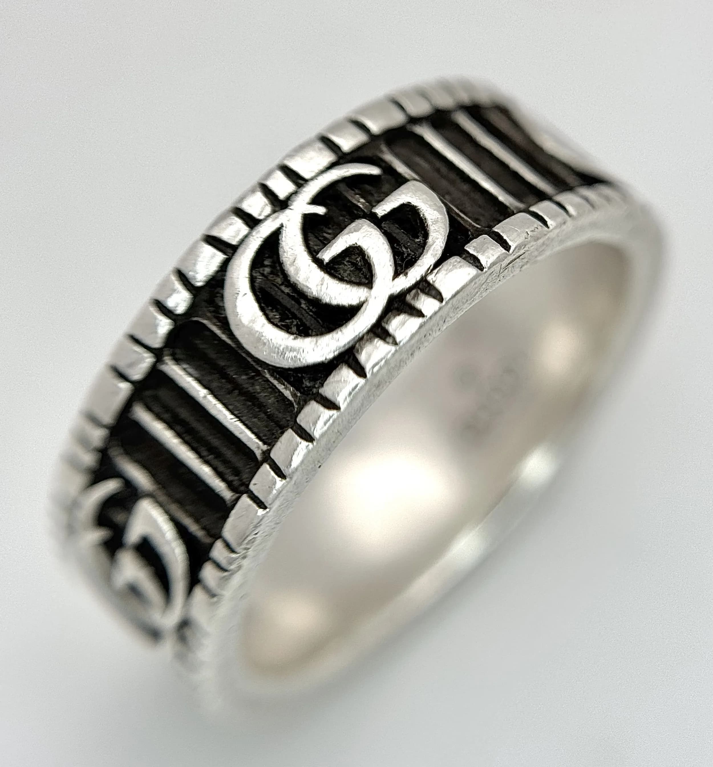 A Sterling Silver Gucci Monogram Band Ring. 8mm width. Size R. 7.9g total weight. Ref: 029554.