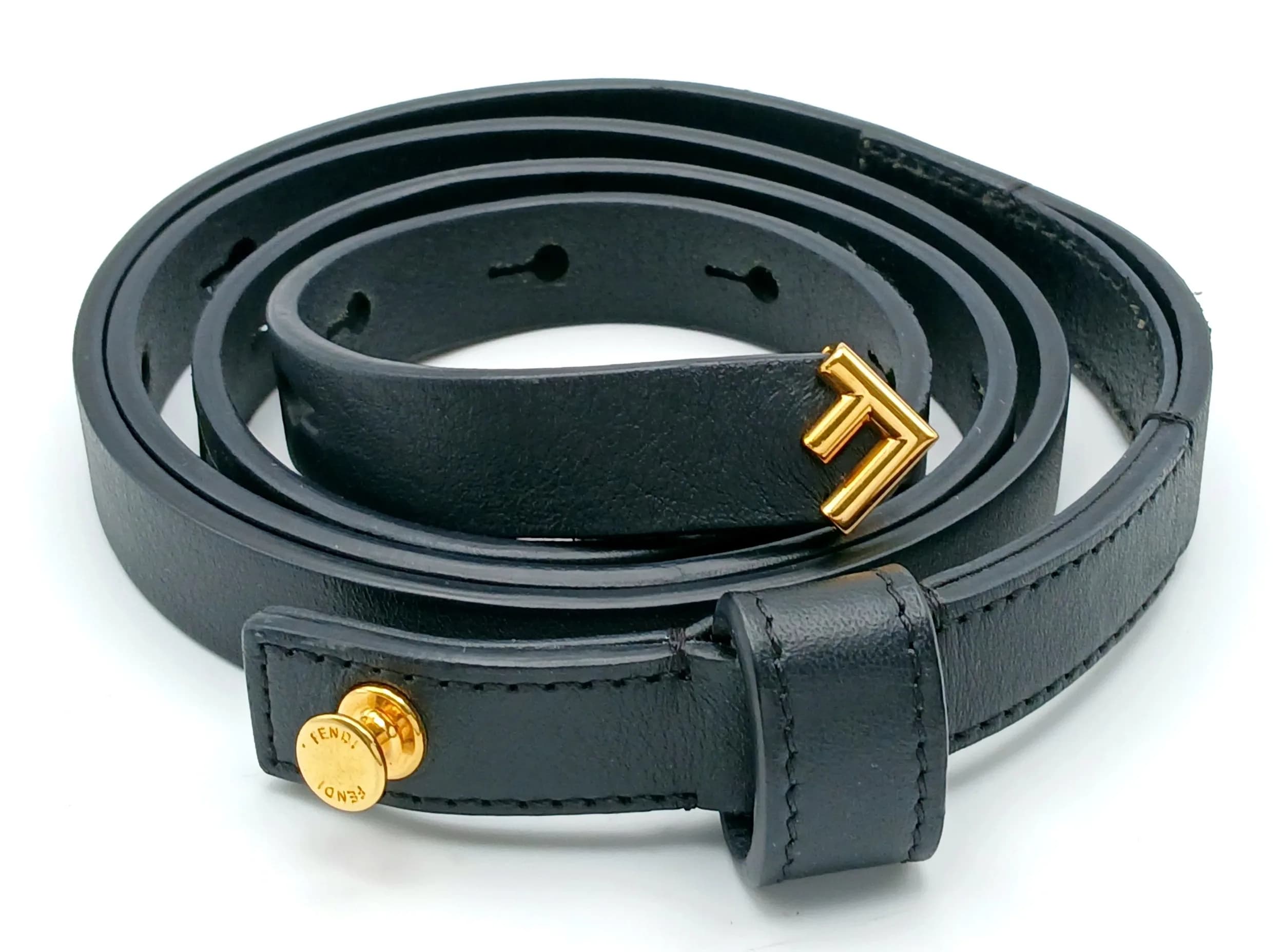 A Fendi Black Leather Belt. Black leather with gold-toned hardware and adjustable buckle fastening. Approx. 130cm total length. Some signs of wear to the leather and scratches to the hardware. Comes with a dust cover. Please see photos or request a condition report. Ref: 29427.