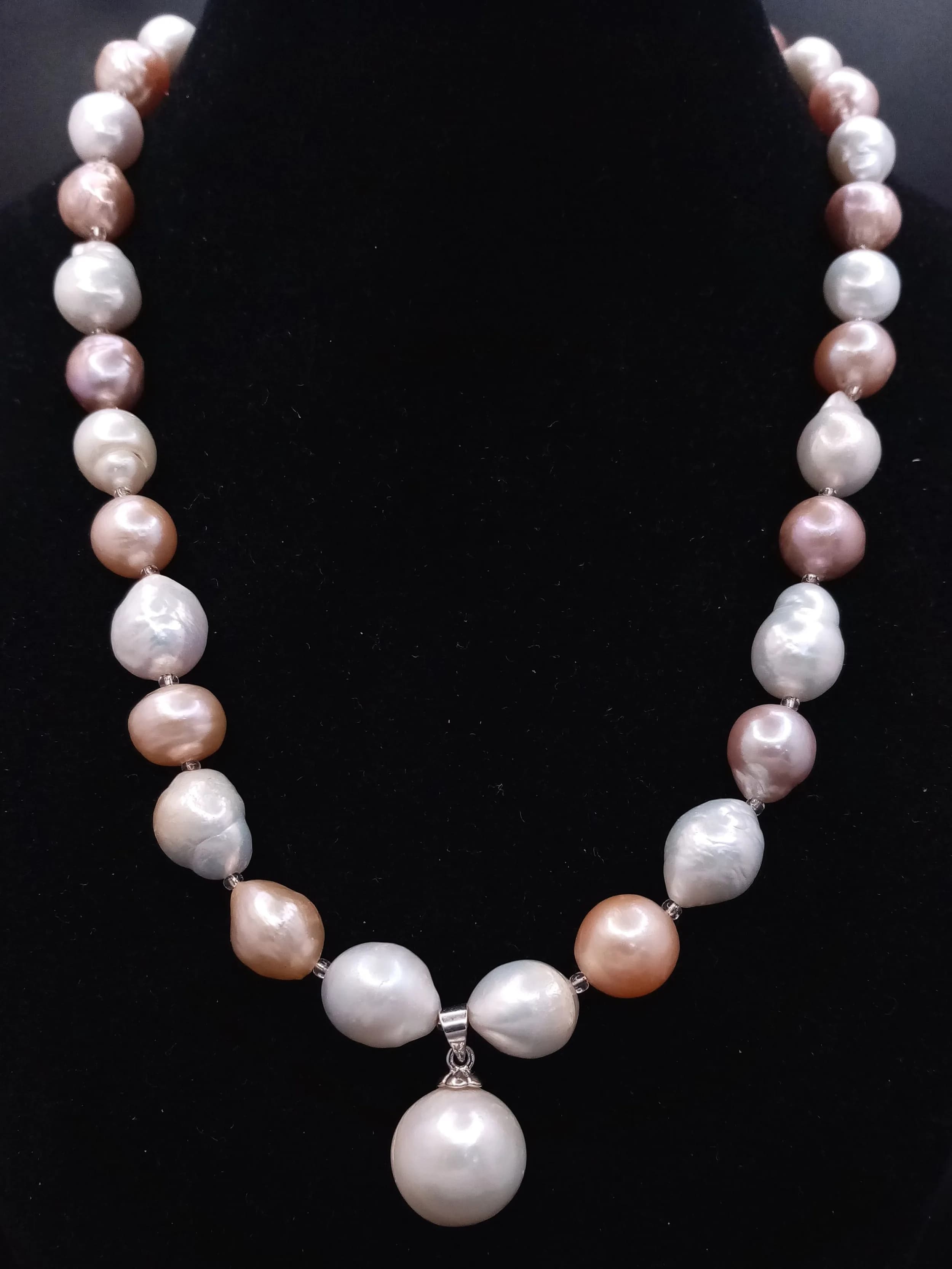 A classic single strand of large Multicolour Freshwater Pearl Necklace. Approx 43cm in length, strung with mixed cream, gold and bronze tone baroque freshwater pearls, with a pearl drop pendant and decorative silver tone floral box clasp.