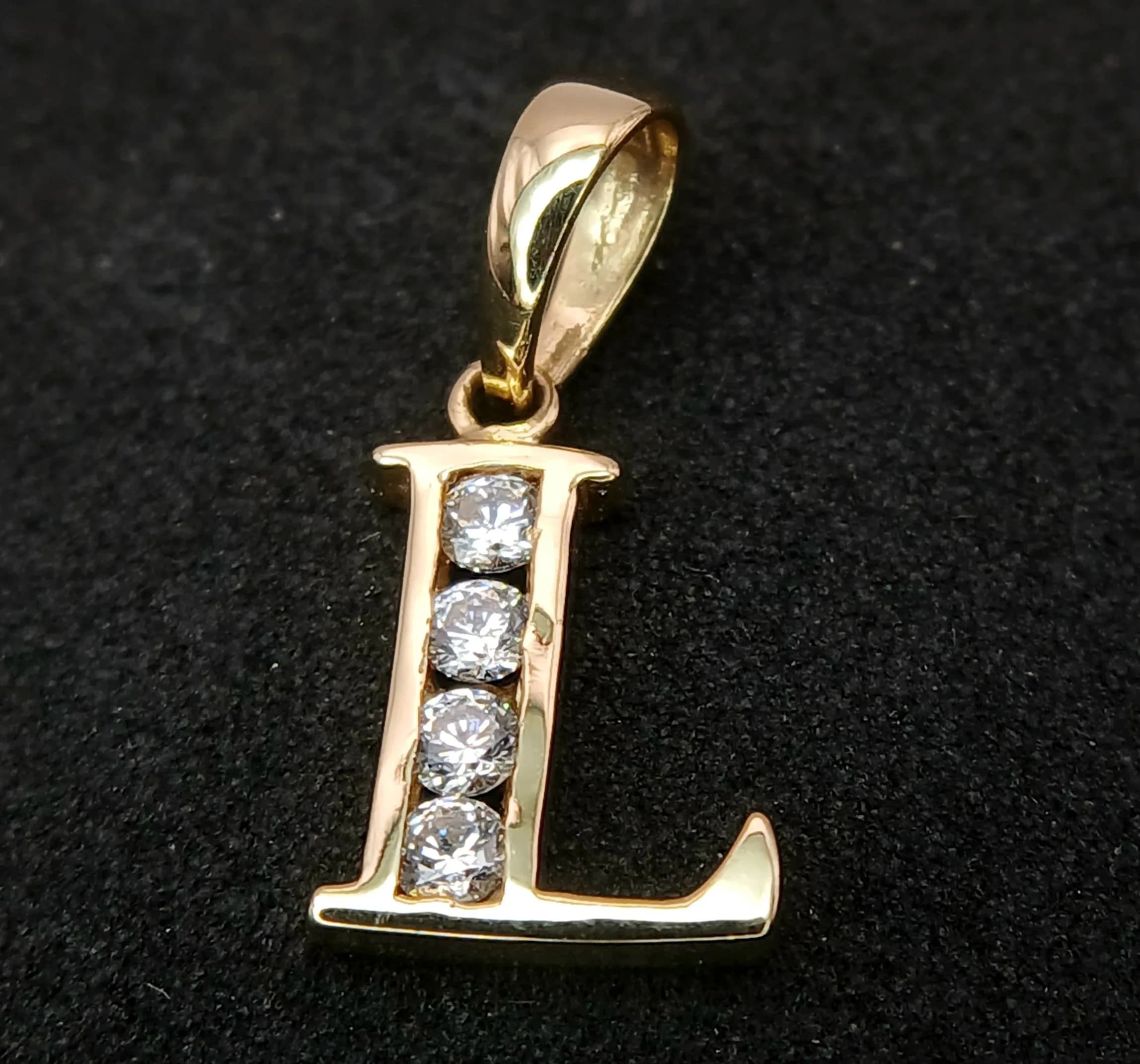 A 14k Yellow Gold Diamonique Cubic Zirconia Letter ‘L’ Pendant. 1.6cm drop, 8mm wide. Set with Diamonique grade CZ therefore better quality than standard CZ giving Diamond appearance. Gross weight 0.68 grams.