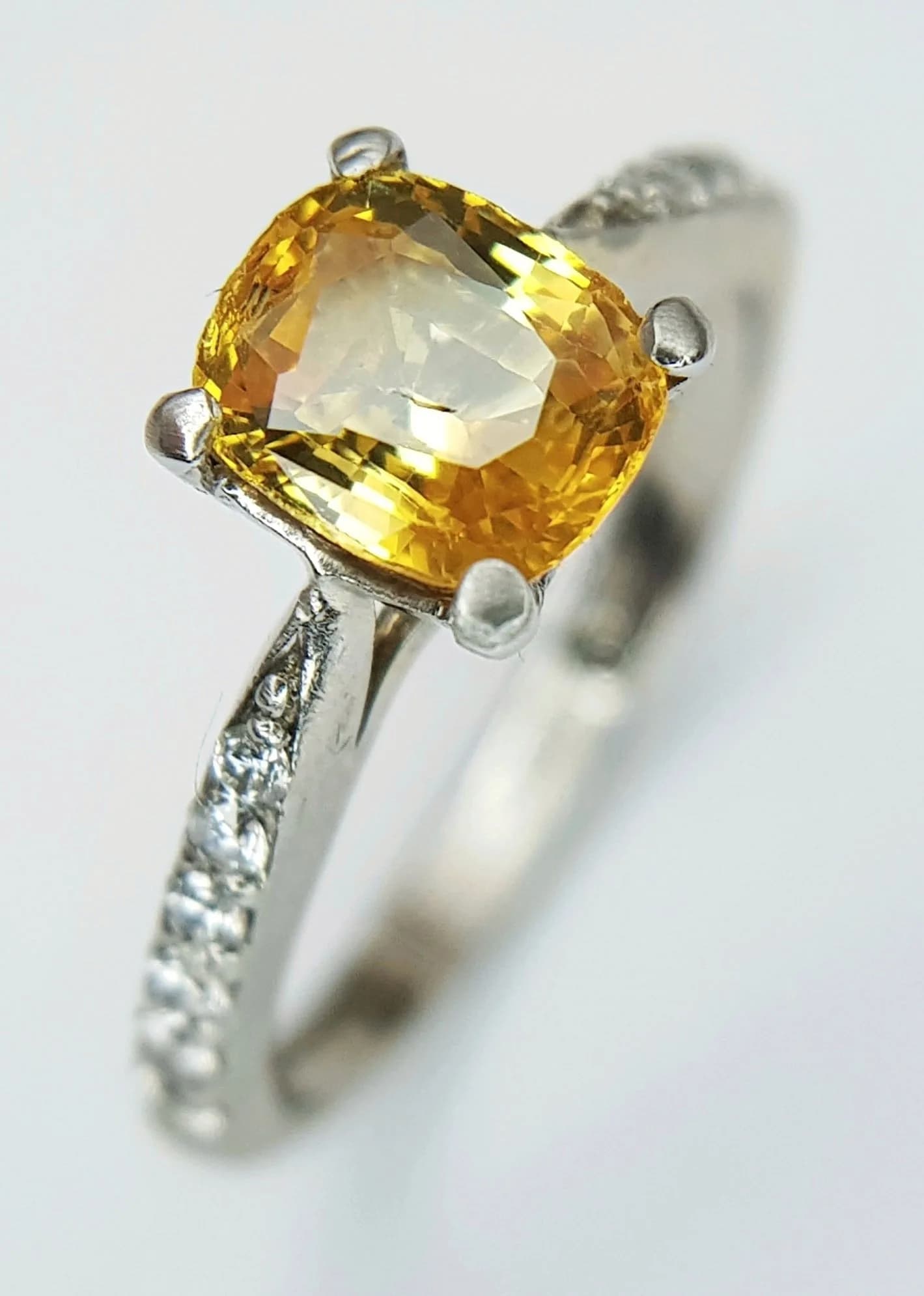 A Platinum and Yellow Sapphire Solitaire Ring. A 1ct cushion cut yellow sapphire with diamond accents on shoulders. Size G 1/2. 3.1g total weight. Ref:15171806.