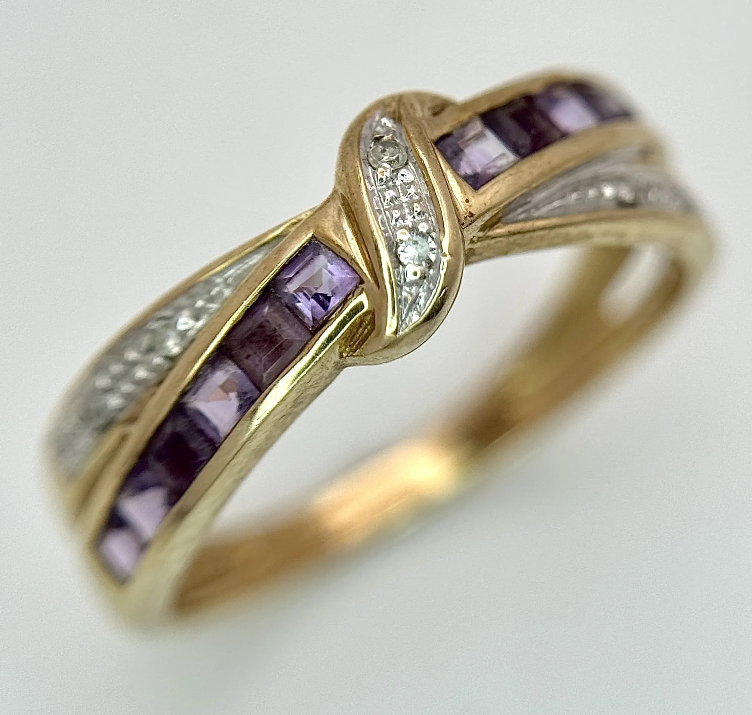 A 9K YELLOW GOLD, DIAMOND AND AMETHYST SET, CROSSOVER KNOT DESIGN RING. 2.1G, SIZE M. S/A 1709 - 2