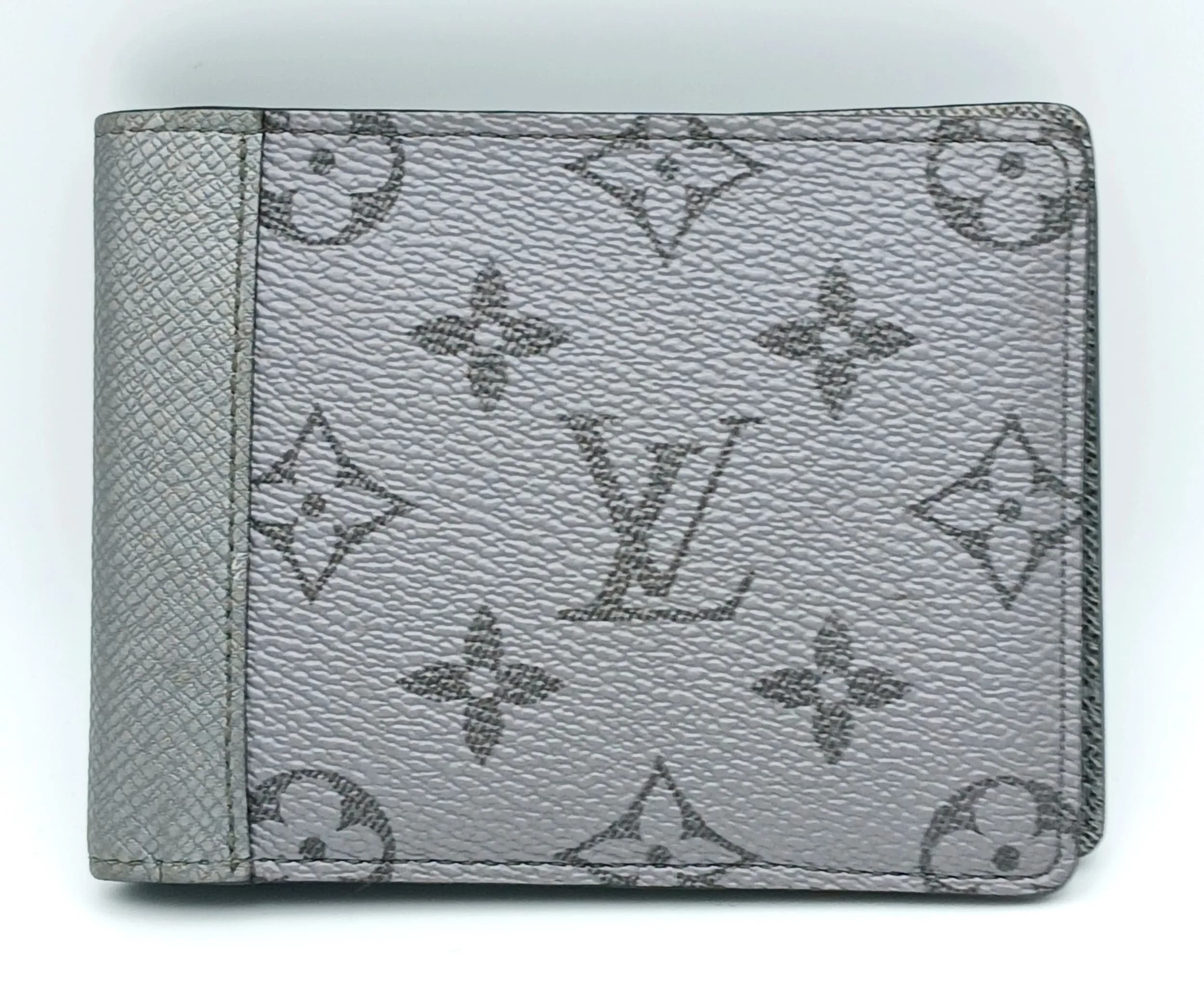 A Grey Louis Vuitton Monogram Eclipse Multiple Wallet. Grey Monogram Eclipse coated canvas exterior with black leather trim. Grey leather interior featuring multiple card slots, note compartment and additional slip pockets. Approx. 12cm length x 9cm height (when closed). Few tiny marks to the leather but in very good condition overall. Please see photos or request a condition report. Ref: 29457.