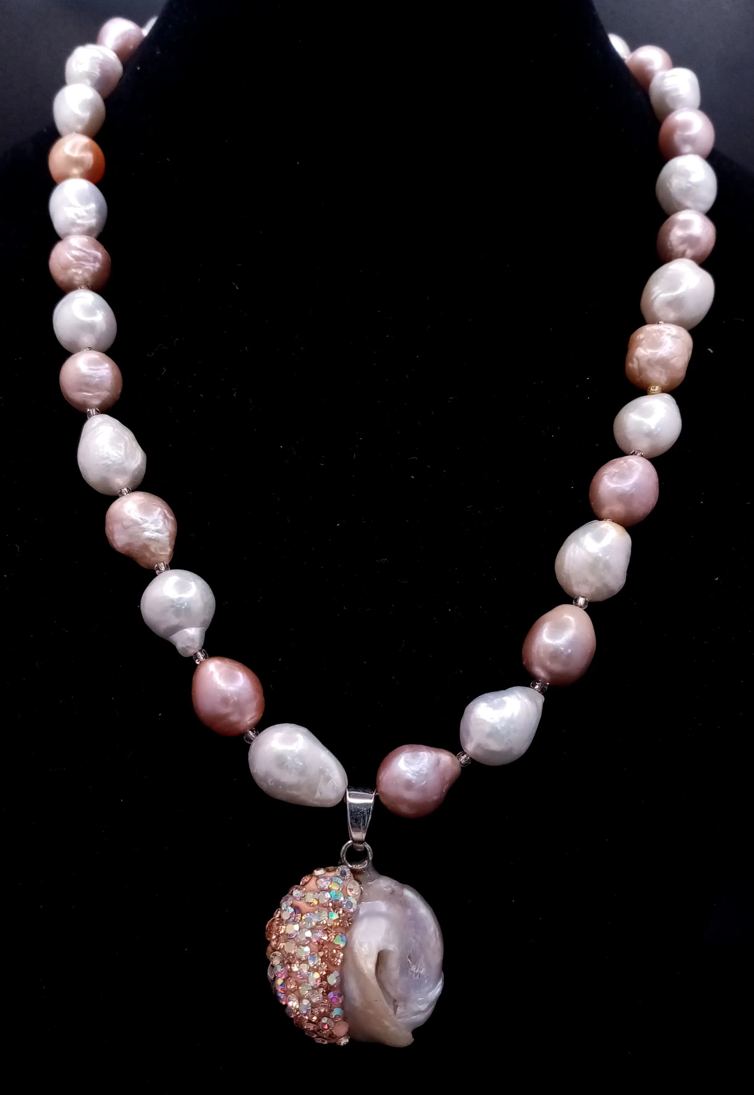 An unique Multicolour large Baroque Freshwater Pearl Necklace. Approx 45cm in length, strung with irregular cream, peach and grey freshwater pearls and fitted with a decorative floral box clasp. With pearl and stone set drop pendant.