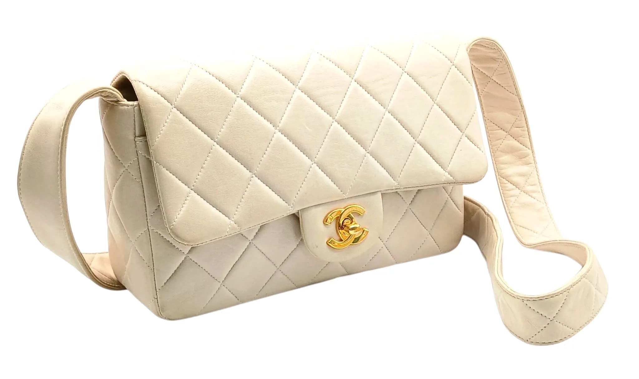 A Chanel Cream Quilted Lambskin Single Flap Shoulder Bag. Cream diamond-quilted lambskin leather exterior with gold-toned CC turn-lock closure, rear pocket and a single flat leather shoulder strap. The flap opens to a cream leather interior with one main compartment, a zipped inner side pocket, an open inner side pocket and a slip compartment. Size approx: 22cm length x 15cm height. Signs of creasing, stains and light discolouration to the leather exterior and interior. Please see photos or request a condition report. Ref: 26605