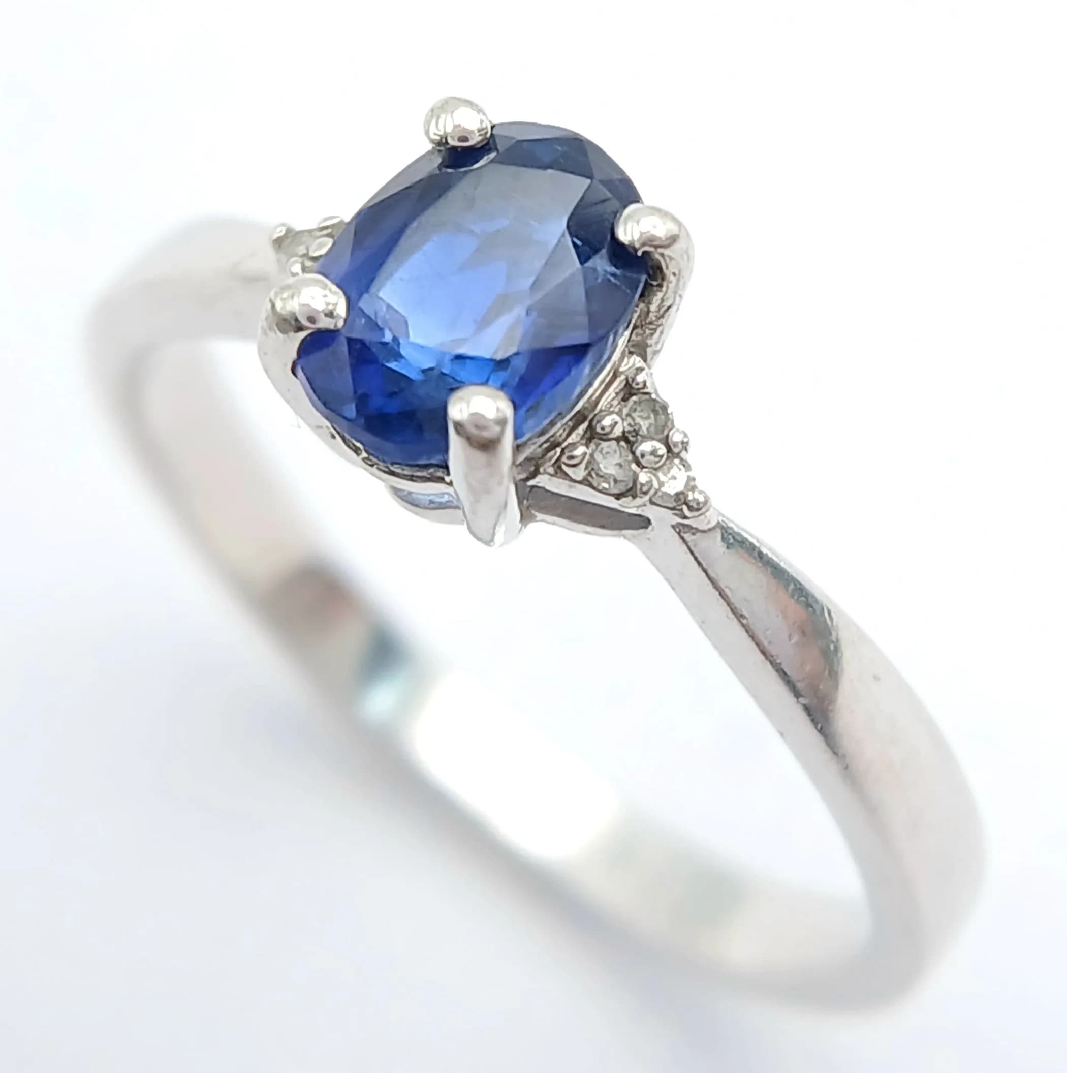 A Sterling Silver Blue Spinel and Diamond Set Ring Size Q. The Ring is set with a 7 x 5mm Sapphire Blue Colour Spinel, circa 1 carat and with Six Round Cut Diamonds set into the shoulders. The Ring weighs 2.47 grams.