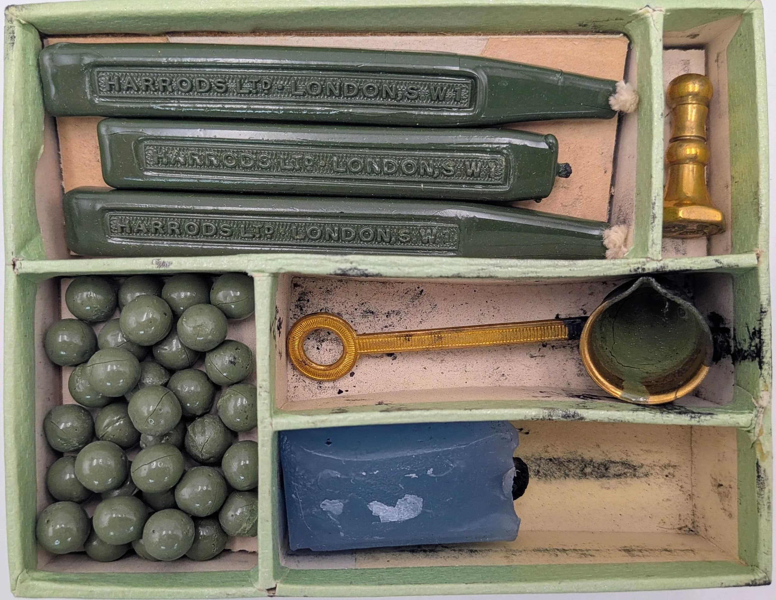 A vintage Harrods of London sealing wax set, featuring the original wax beads and sticks along with the melting tool and an English rose seal stamp, all in original box.