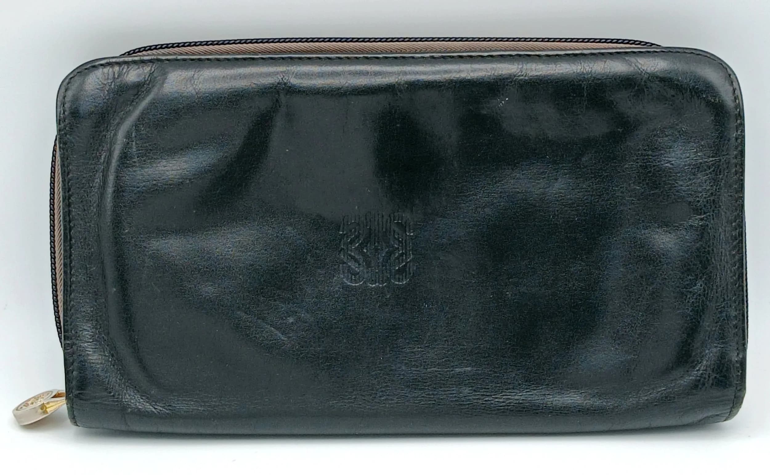 A Black Loewe Leather Travel Wallet. Black leather exterior with gold-toned hardware and zip-around fastening. Black leather interior featuring multiple card slots, document compartments, a zipped pocket and pen holders. Approx. 20.5cm length x 11.5cm height (when closed). Some signs of wear, scratches and marks to the leather. Comes with a dust cover and box. Please see photos or request a condition report. Ref: 29254.
