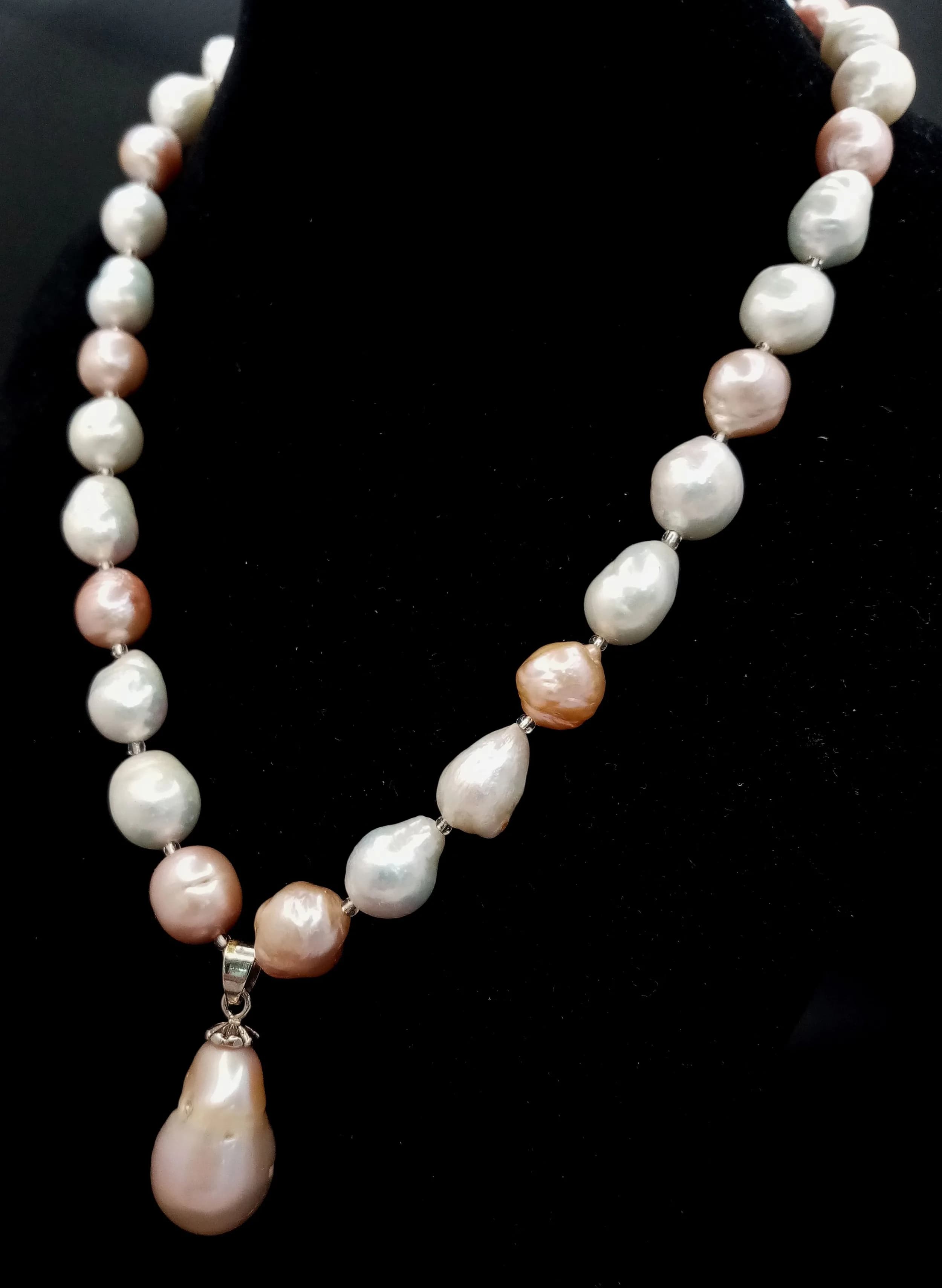 A pretty single strand of Multicolour large Freshwater Pearl Necklace. Approx 44cm in length, strung with cream, peach and bronze tone baroque freshwater pearls, with a pearl drop pendant and decorative floral box clasp.
