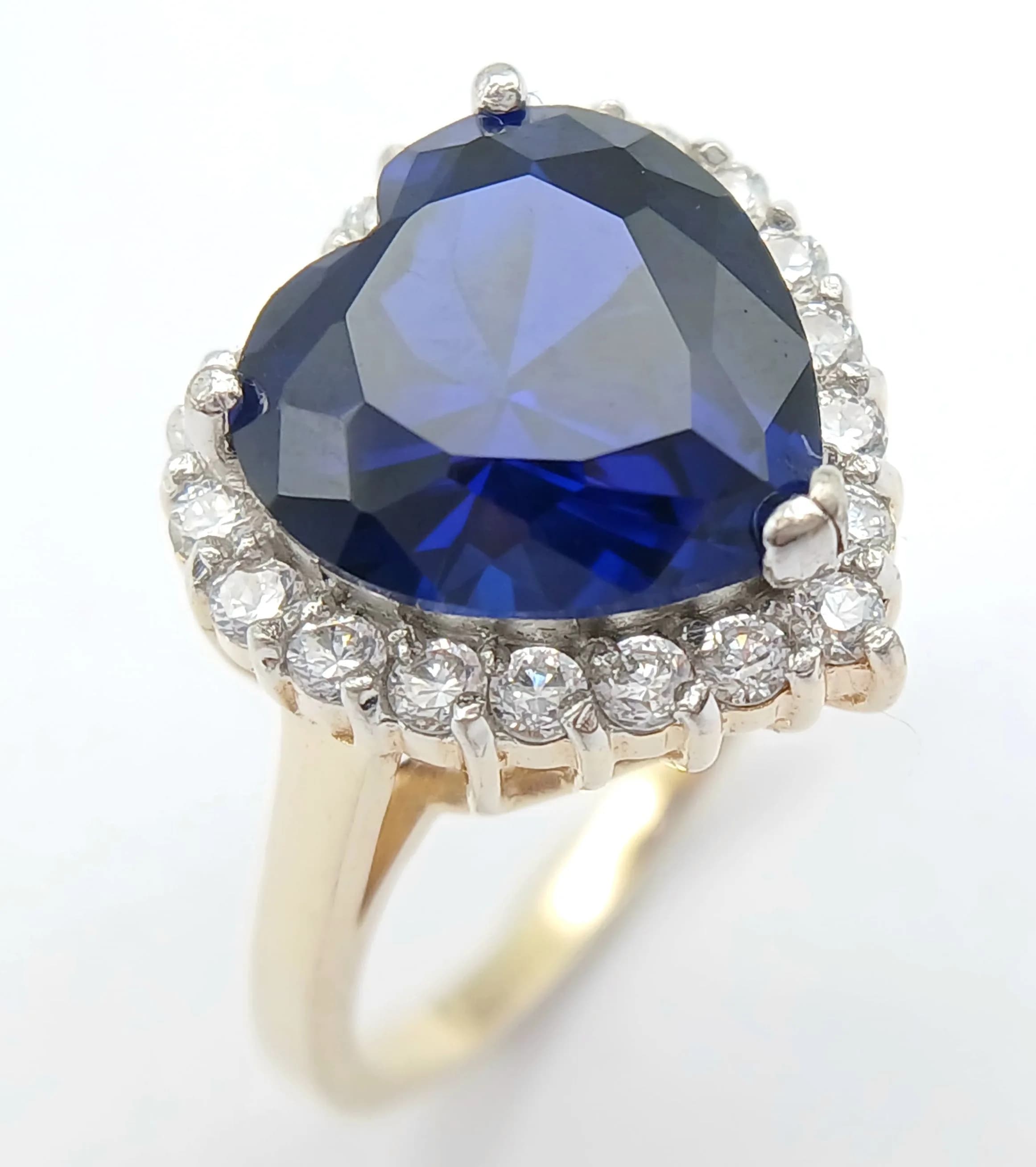 A Gold Gilded Sterling Silver Heart Cut Sapphire and Cubic Zirconia Ring Size U. The Ring is set with a 1.2cm Wide Heart Cut Sapphire surrounded by a halo of White Cubic Zirconia. Gross Weight 5.87 grams.