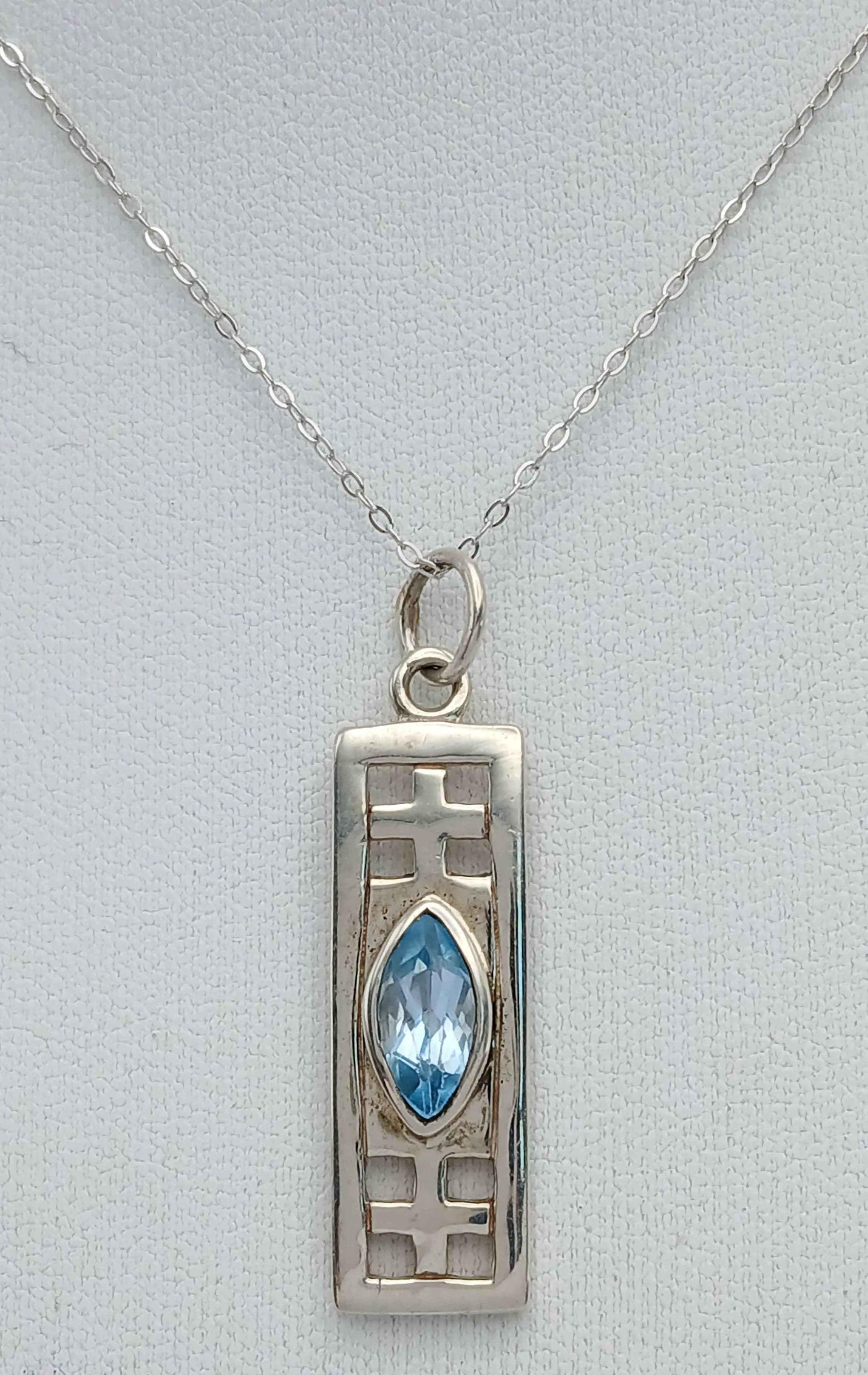 A Charles Rennie Mackintosh Design Sterling Silver and Blue Topaz Celtic Pendant Necklace. 41cm Length Chain. The Pendant measures a 3.7cm drop, 1cm width. Set with a Marquis Cut 10 x 5mm Blue Topaz, approximately 1.25 Carat. Gross Weight 5.03 grams.
