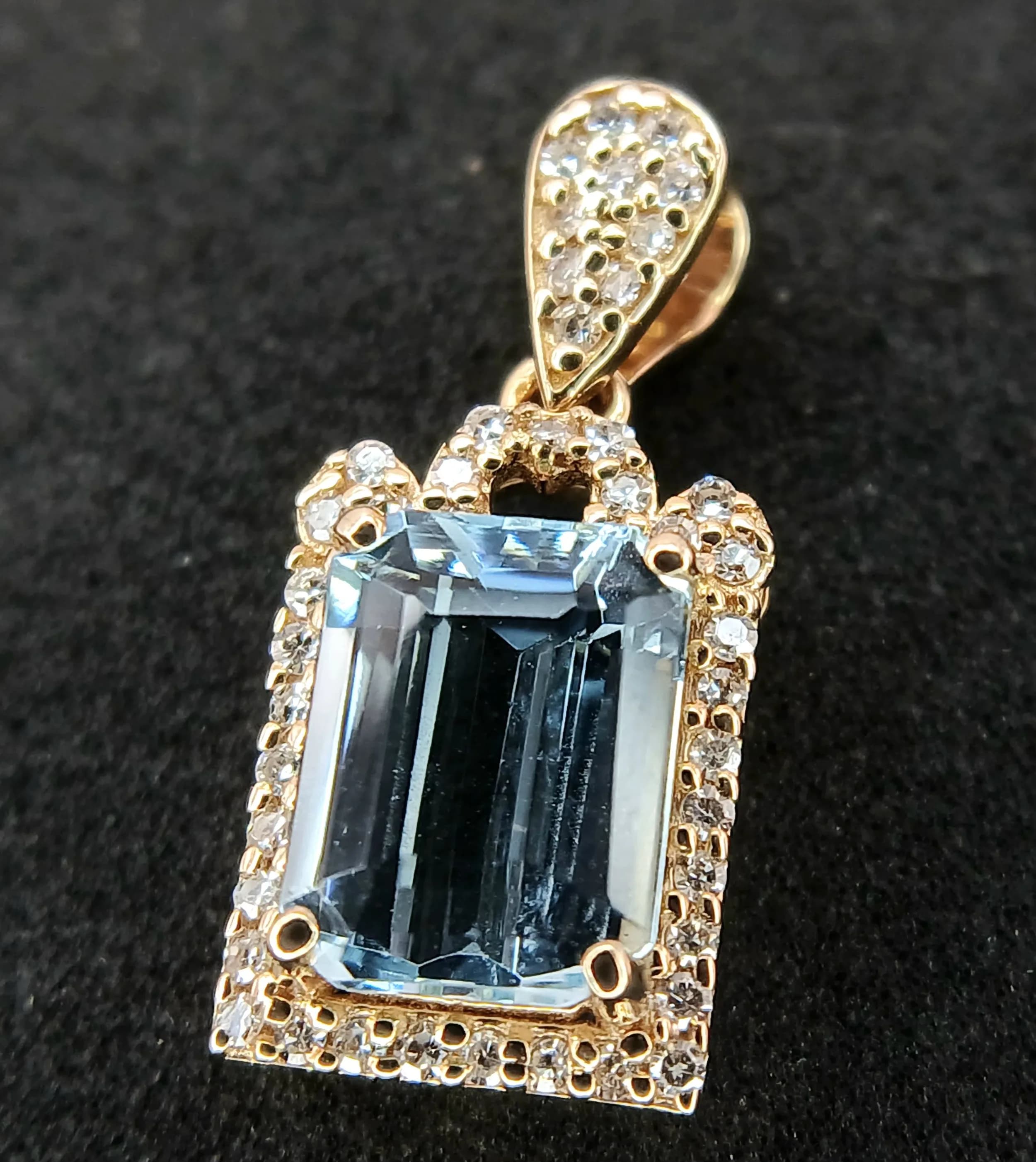 A 14K Gold, Aquamarine and Diamond Pendant. 1.44ct octagon step cut aquamarine with a 0.14ctw diamond surround. 2cm. 1.48g total weight. Comes with an HRD Antwerp certificate. Ref: CLP-12379.