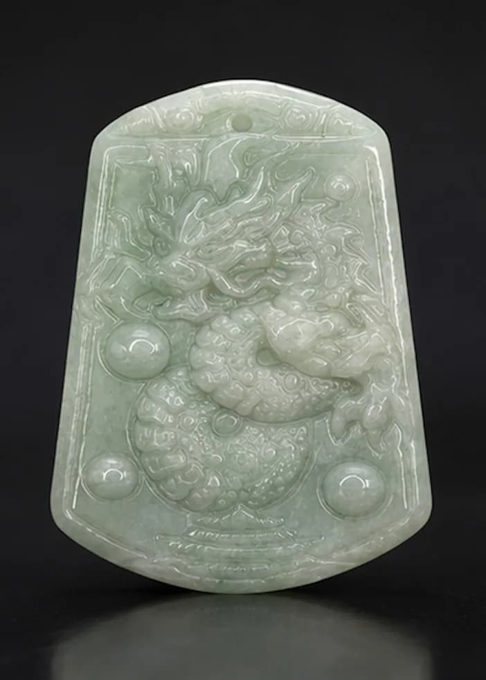 A Jade ‘Dragon’ Pendant. Carved from pale celadon jade. Approximately 4cm × 2.5cm. Weight: approximately 8.7g. Come with an adjustable cord.