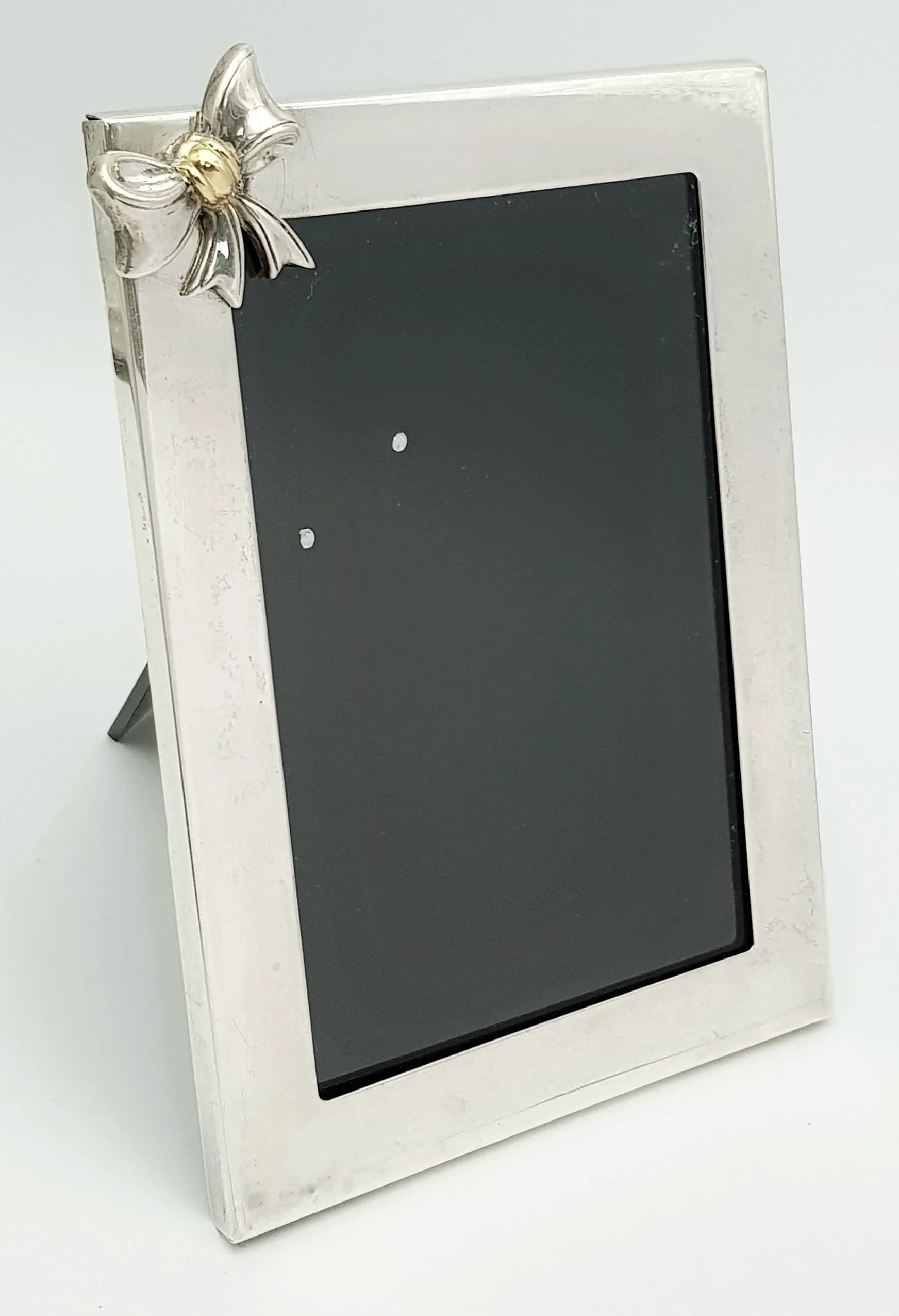 A TIFFANY&CO SILVERPHOTO FRAME WITH CUTE BOW DECORATION . 18 X 13cms