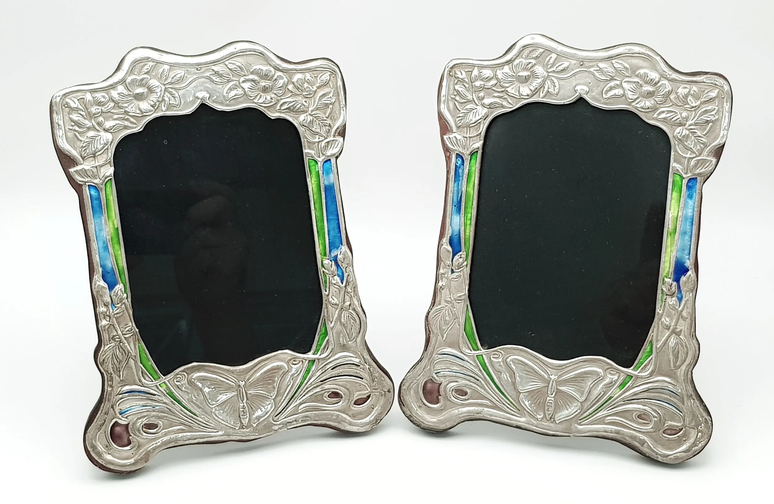 A MATCHING PAIR OF ART NOUVEAU SILVER PHOTO FRAMES WITH COLOURED ENAMEL WORK . 16 X 21cms