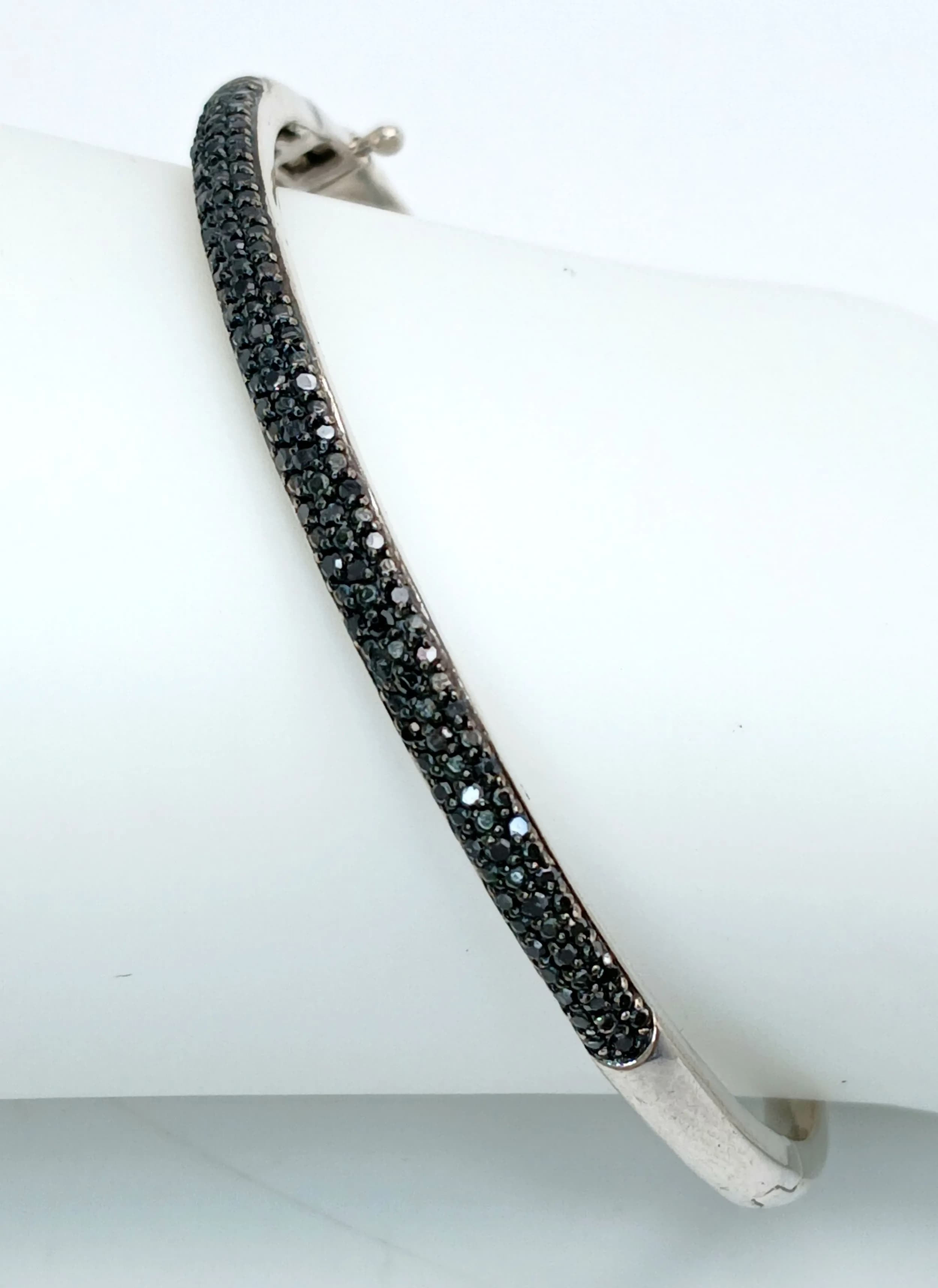 A STERLING SILVER, STONE SET BANGLE. WITH A SAFETY CATCH. 12.4G. 5778