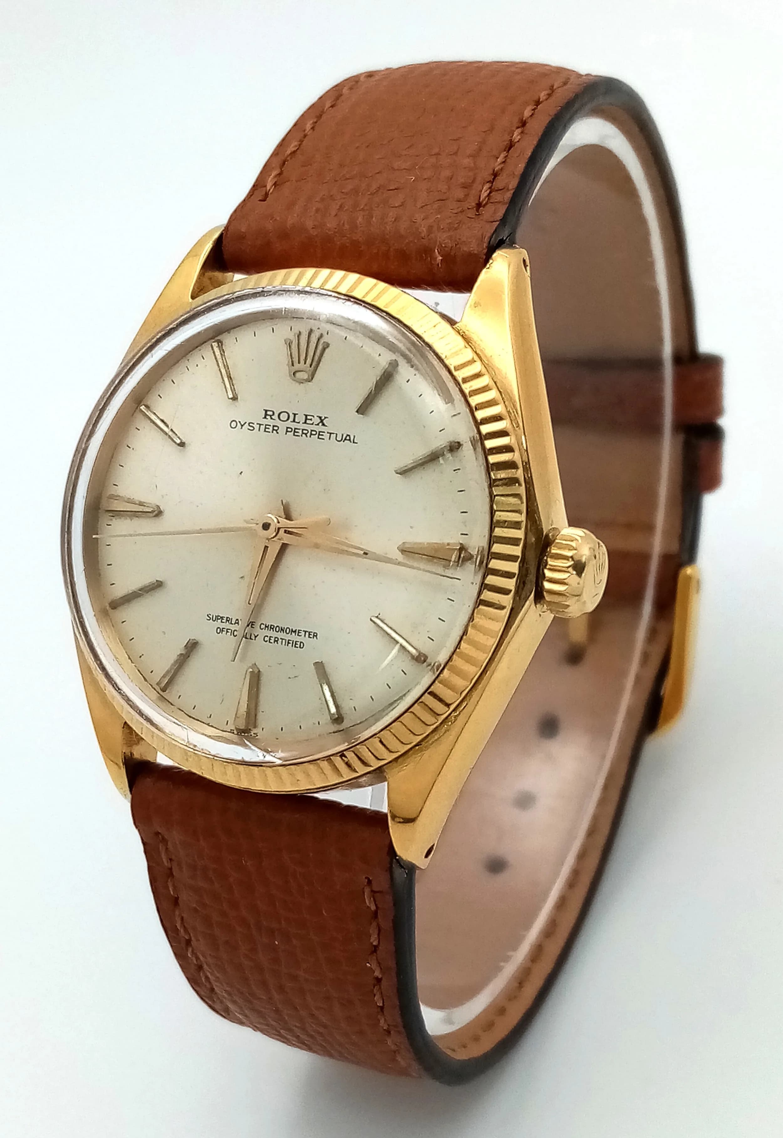 A Vintage 18K Gold Rolex Oyster Perpetual Gents Watch. Brown leather strap. 18K gold case - 34mm. Fluted bezel. Gold tone dial. Automatic movement. In working order.