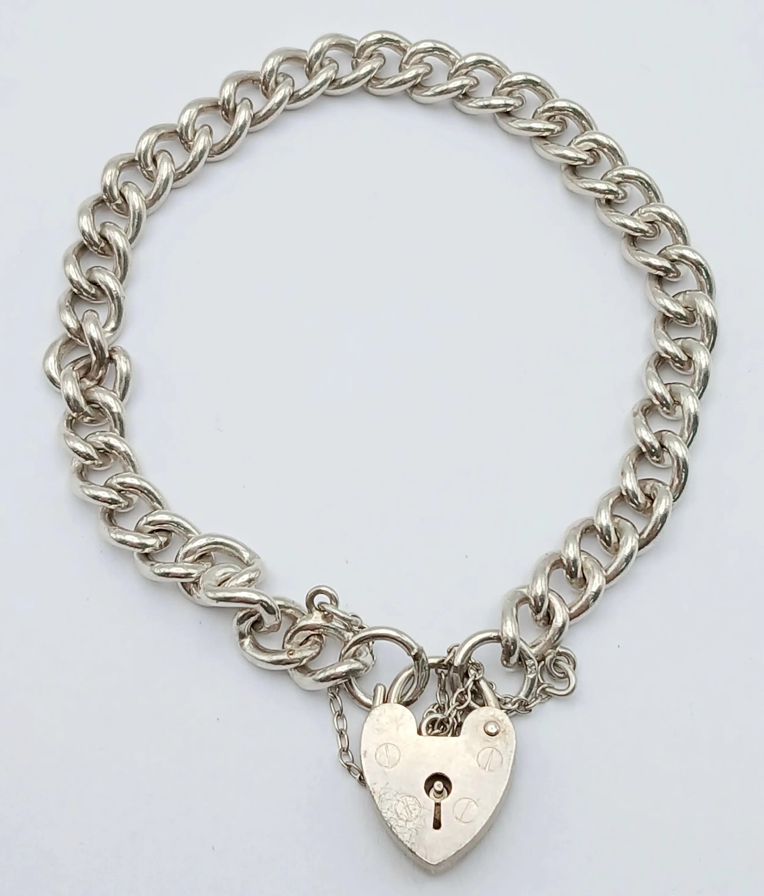 A STERLING SILVER, CURB LINK, CHARM BRACELET WITH HEART PADLOCK CLASP. READY TO START BUILDING YOUR OWN COLLECTION OF CHARMS. 18.8G. 3841