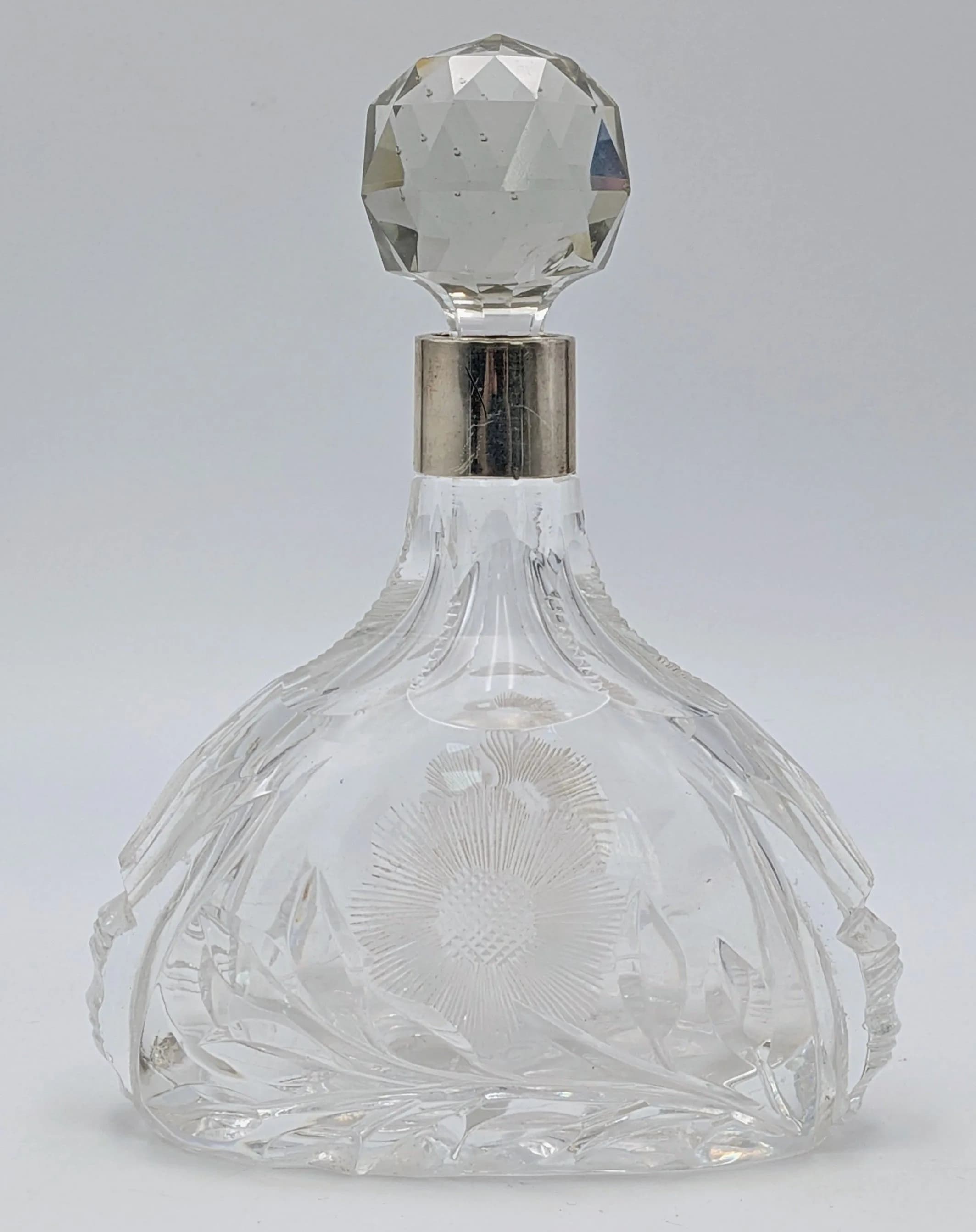 An Antique Cut-Glass Small Decanter with a Large Faceted Crystal Stopper - and a silver neck collar (800 silver). 18cm tall.