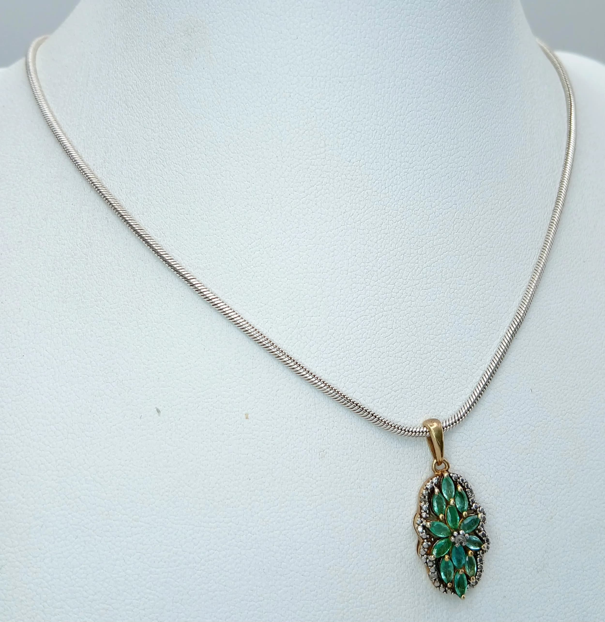 A Beautiful 925 Sterling Silver Green Stone Floral Pendant Necklace - 32cm Length. Features a floral pendant set with marquise cut green stones and white accent stones on a fine snake chain. The pendant measures 2cm x 1cm. Gross weight 9.89 grams.